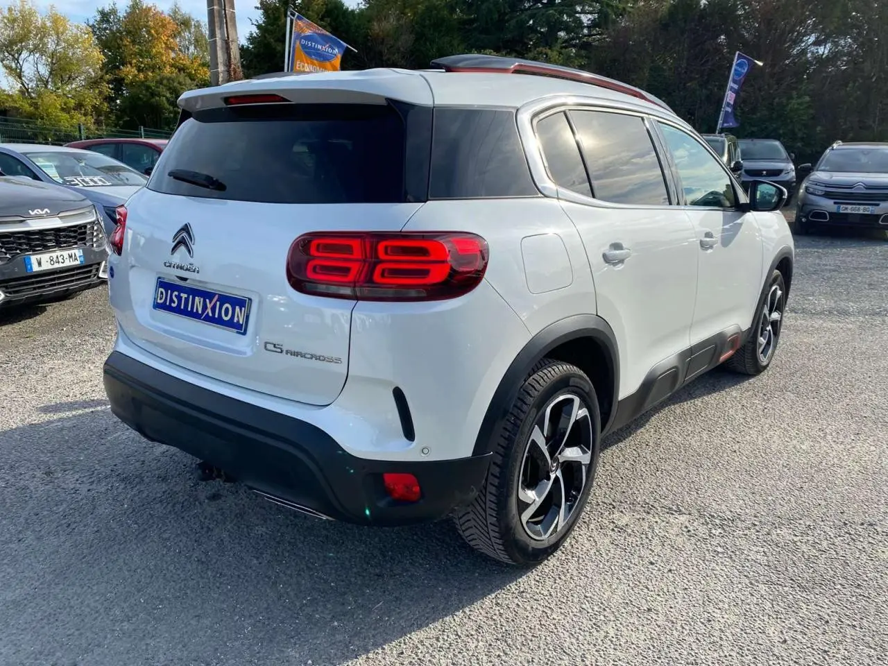 Vue 3/4 arrière droite d'un Citroën C5 Aircross blanc avec jantes bi-ton et inserts rouges distinctifs.