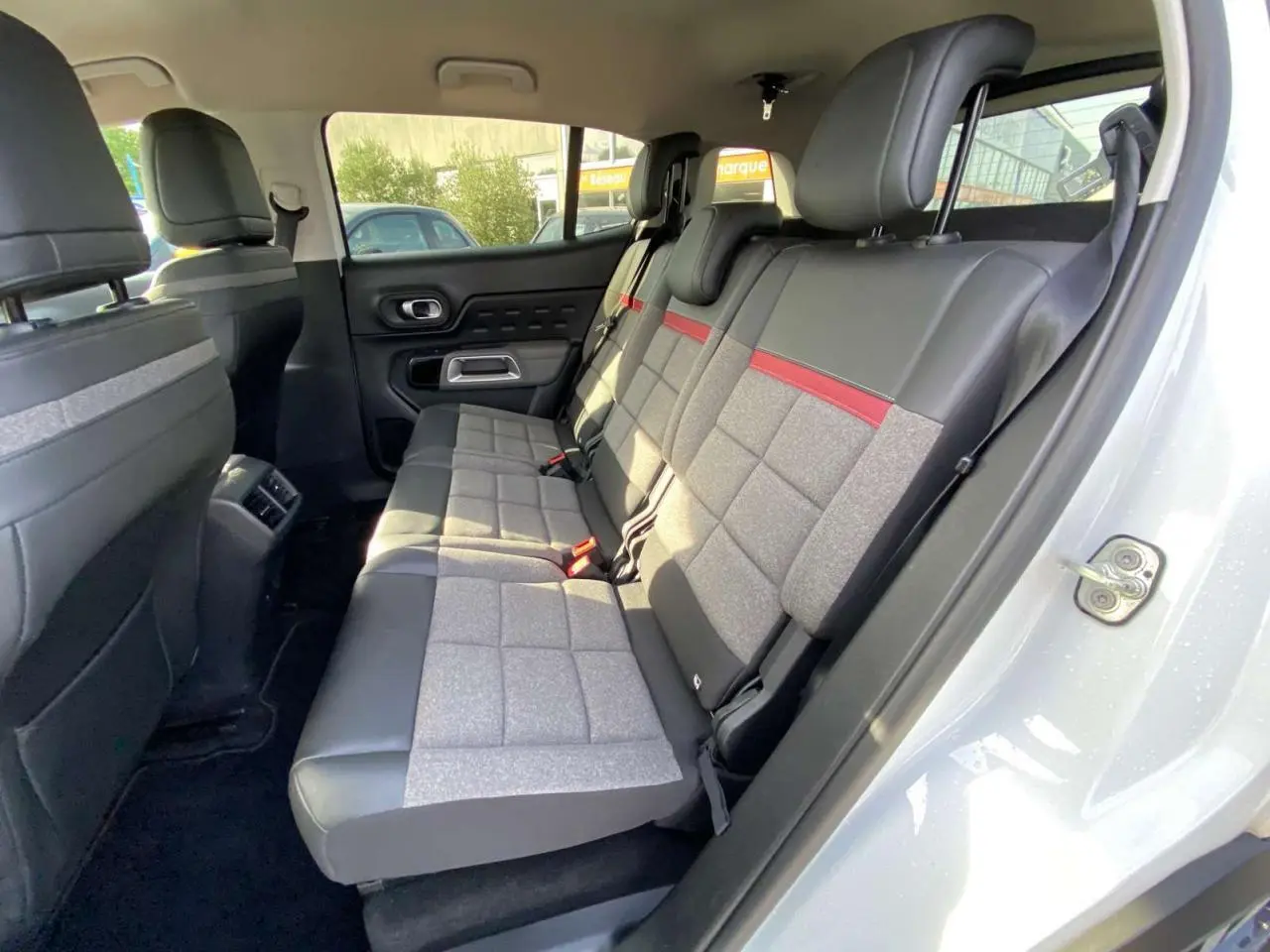 Vue intérieure côté droit des sièges arrière du Citroën C5 Aircross 2021 avec sellerie cuir et tissu gris à bande rouge.
