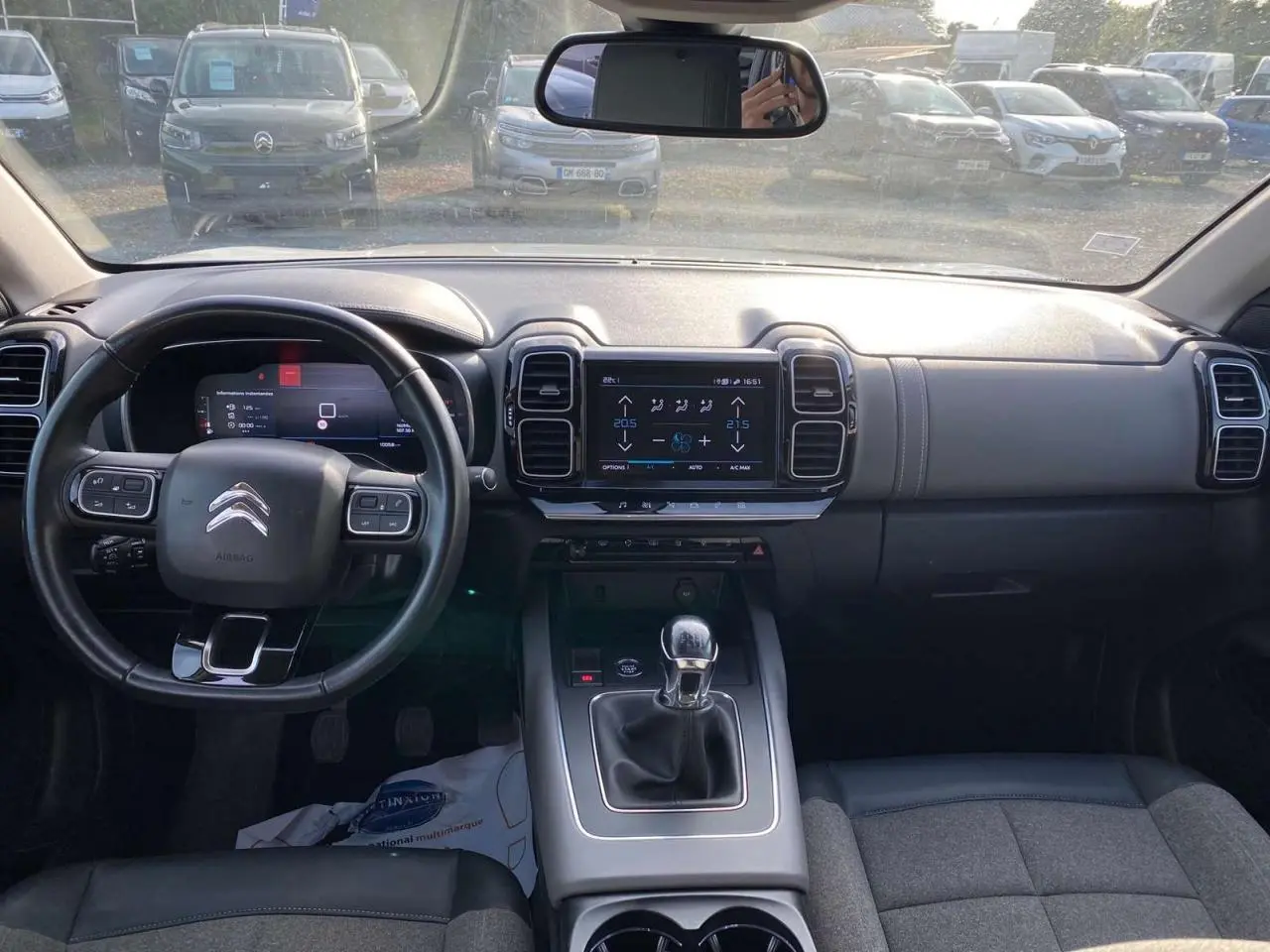 Vue intérieure avant du Citroën C5 Aircross blanc avec tableau de bord noir, volant cuir et boîte manuelle.