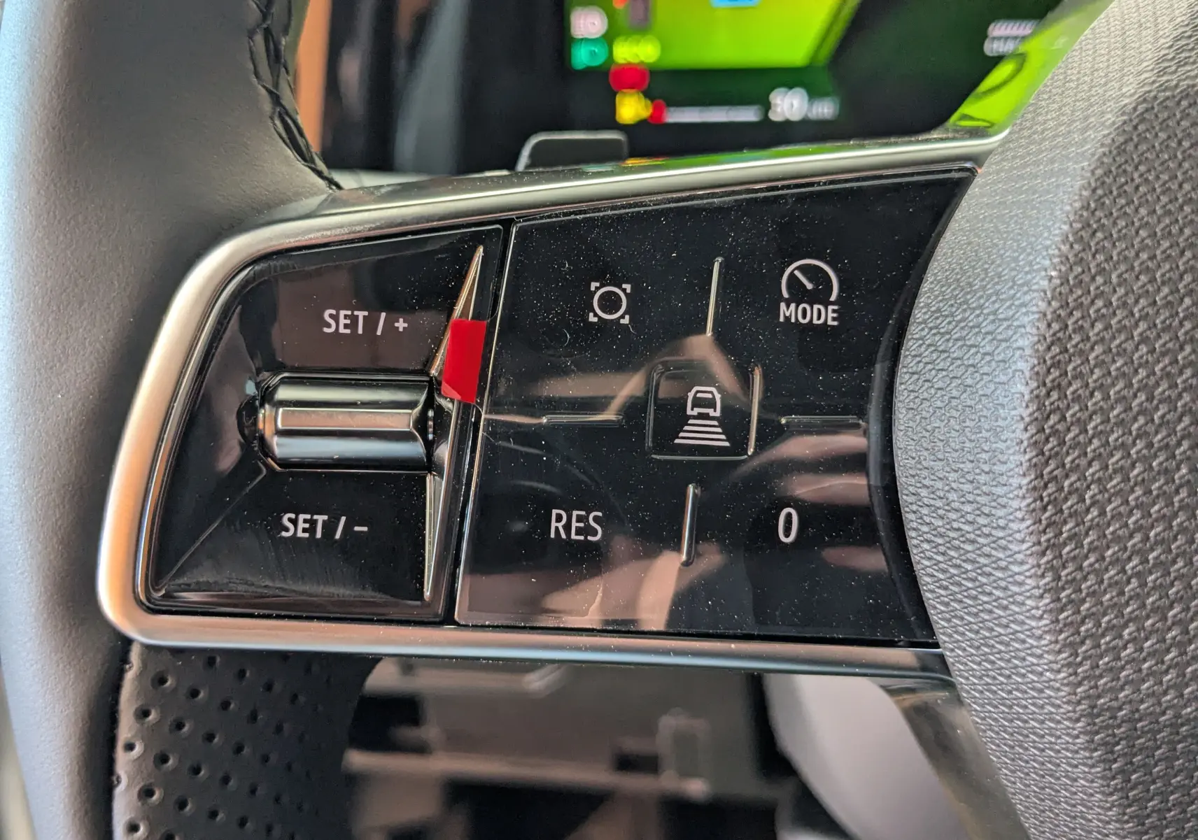 Gros plan sur les commandes de régulateur de vitesse au volant du Renault Austral blanc nacré, affichage numérique en arrière-plan.