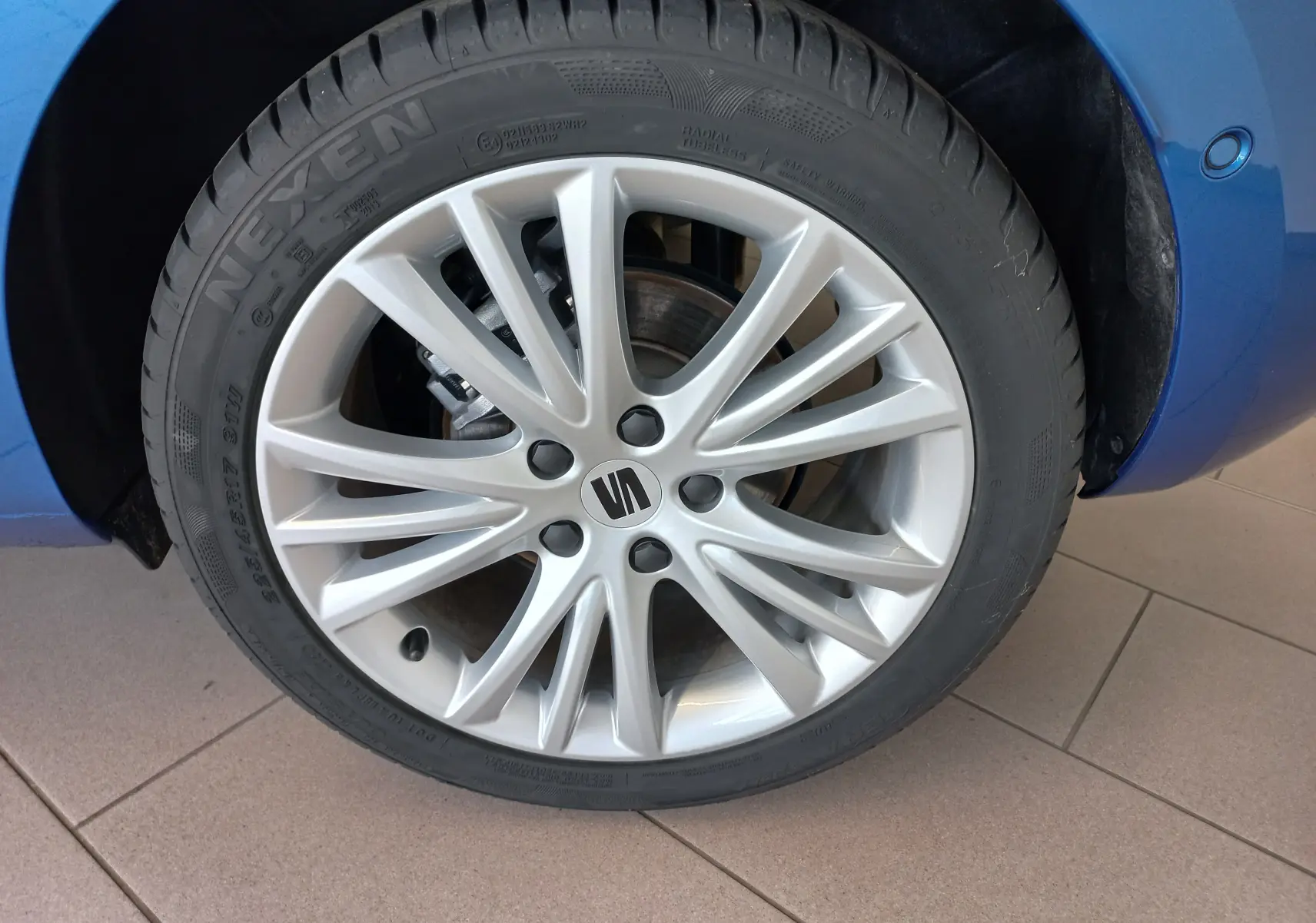 Gros plan sur la roue avant droite d'une SEAT LEON Bleu Saphir, mettant en valeur la jante alliage argentée au design fin.