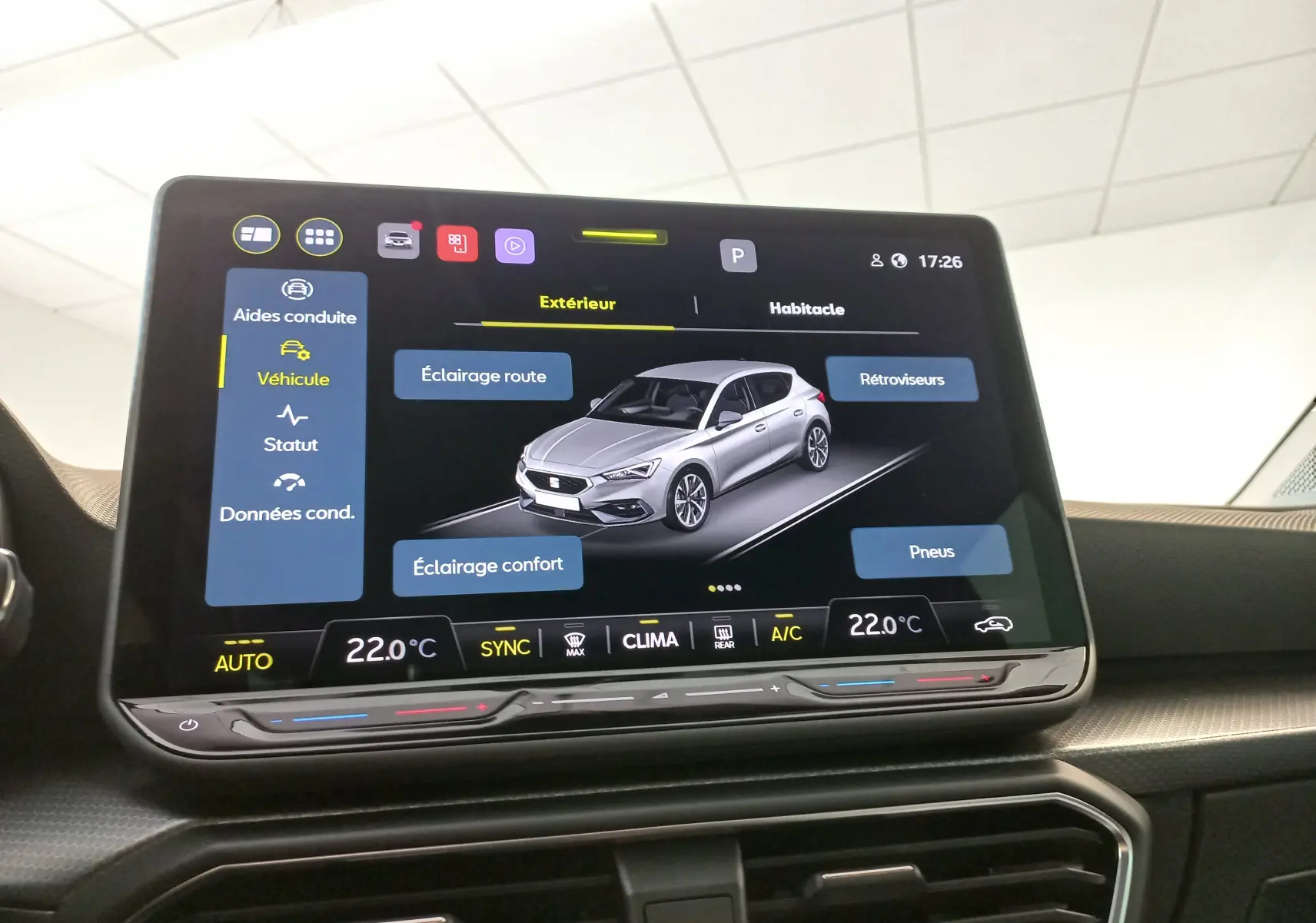 Écran central de la SEAT Leon 2025 affichant les aides à la conduite avec vue 3D du véhicule gris sur fond noir.