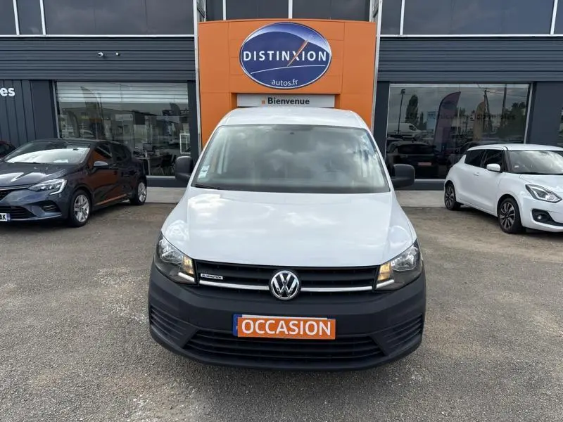 Vue de face d'un Volkswagen Caddy Van blanc Candy avec calandre noire et panneau "OCCASION" orange au pare-chocs.