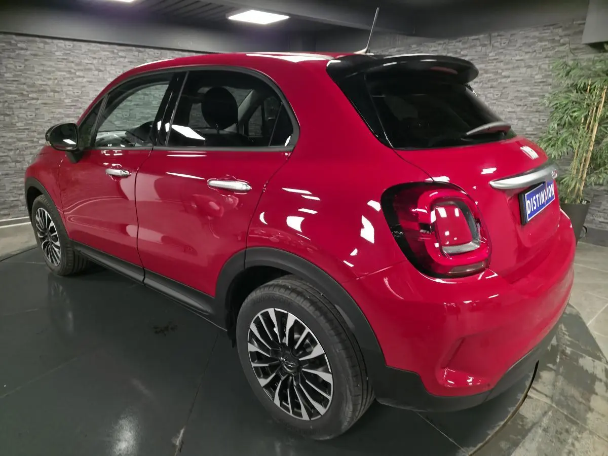 Vue 3/4 arrière droite d'une Fiat 500X rouge Passione avec jantes alliage 17 pouces et vitres surteintées.