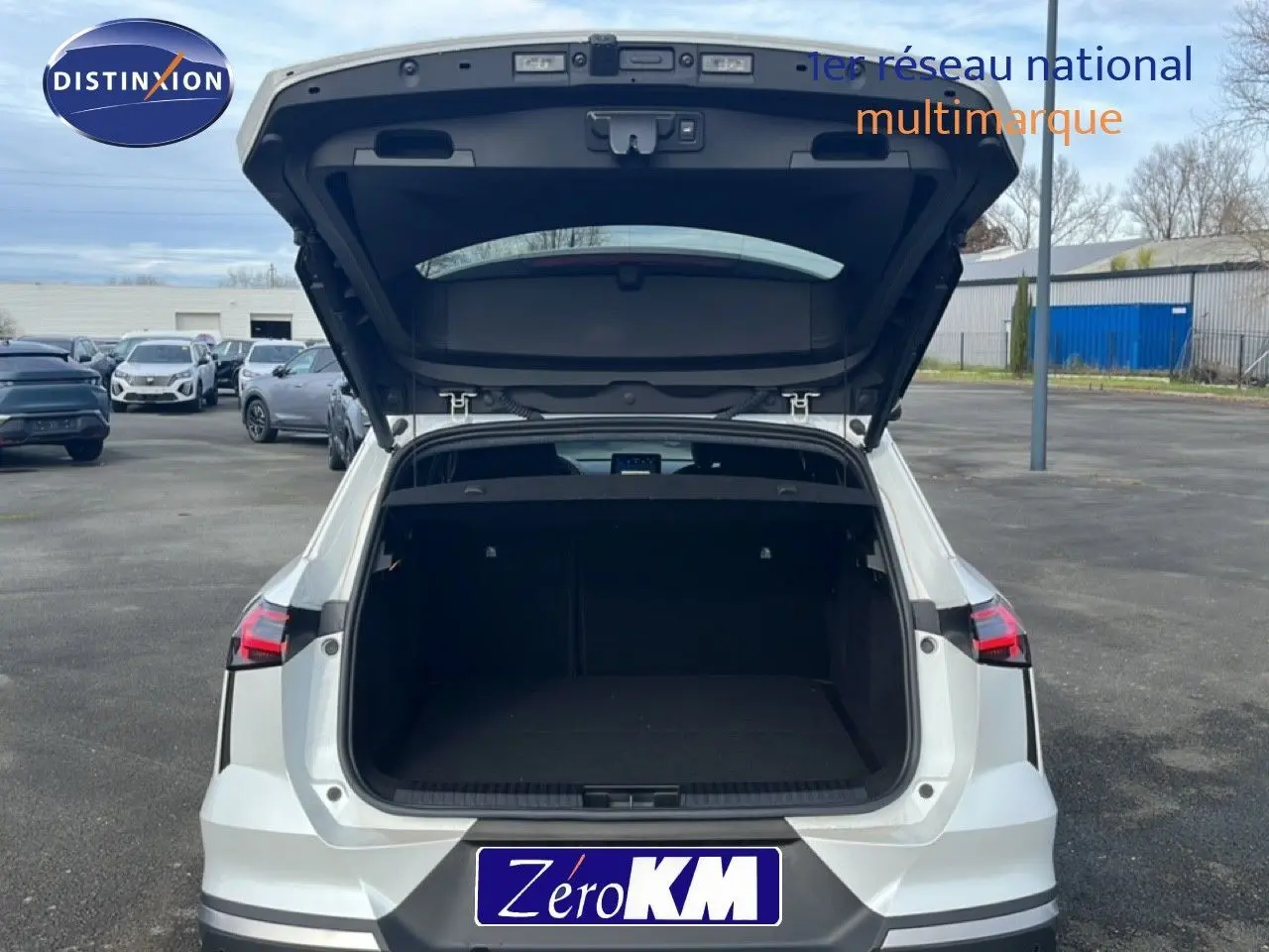 Vue arrière d’un Renault Symbioz blanc nacré métal 2025 avec coffre ouvert montrant un grand espace de chargement vide.