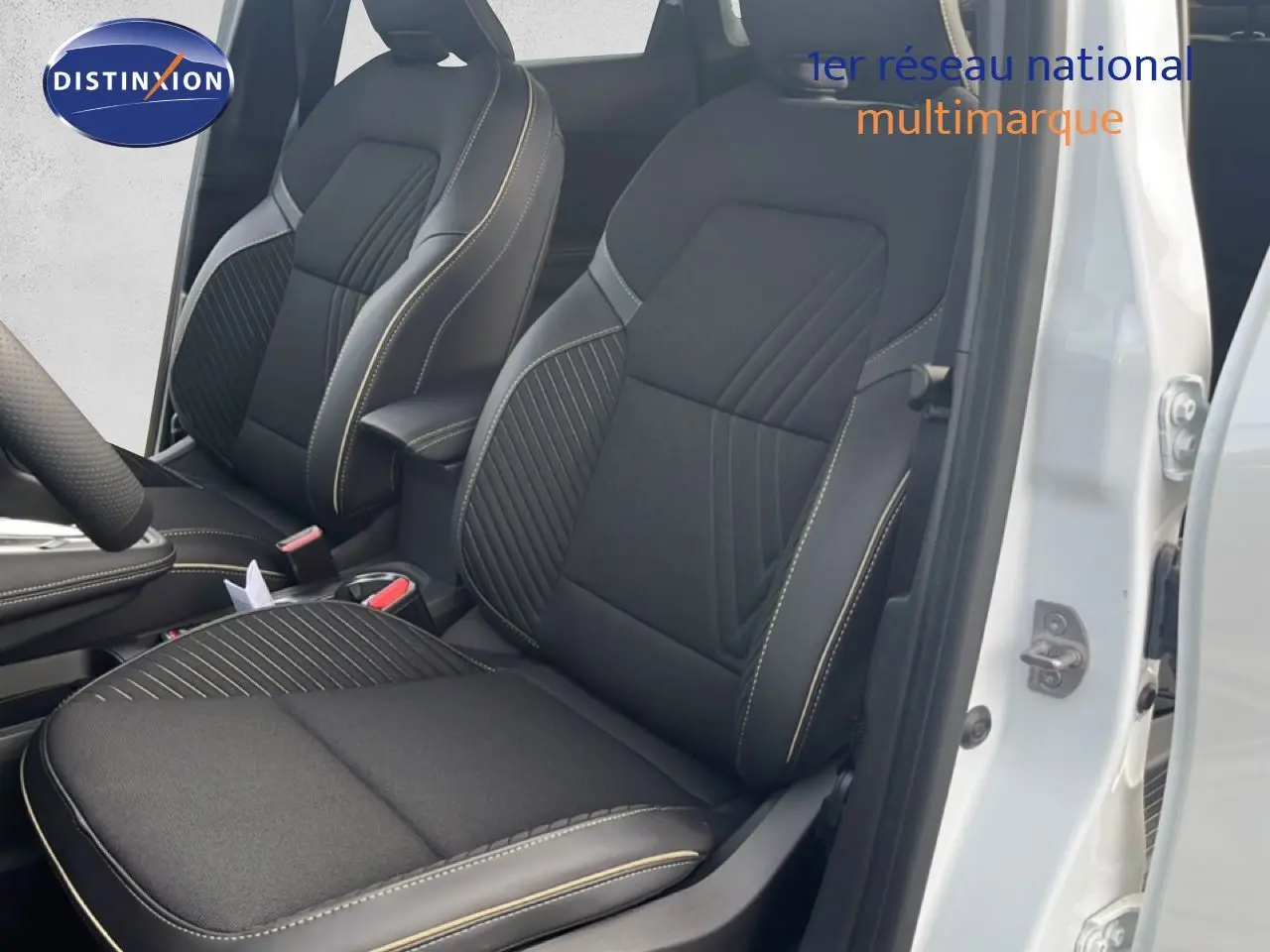 Vue intérieure sur les sièges avant noirs avec surpiqûres claires du Renault Symbioz blanc nacré 2025, porte ouverte côté droit.