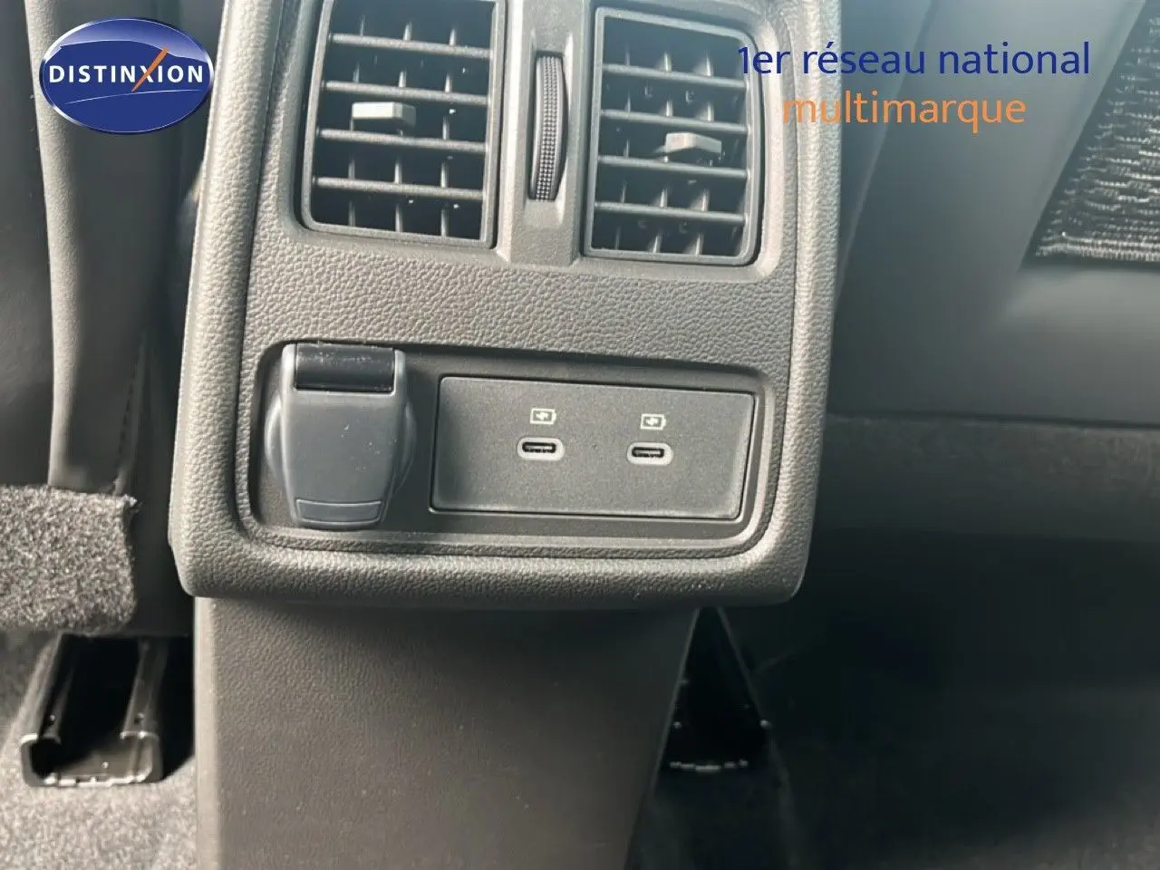 Détail des prises USB et prise 12V sous la grille d’aération arrière dans l’habitacle d’une Renault Symbioz blanc nacré.