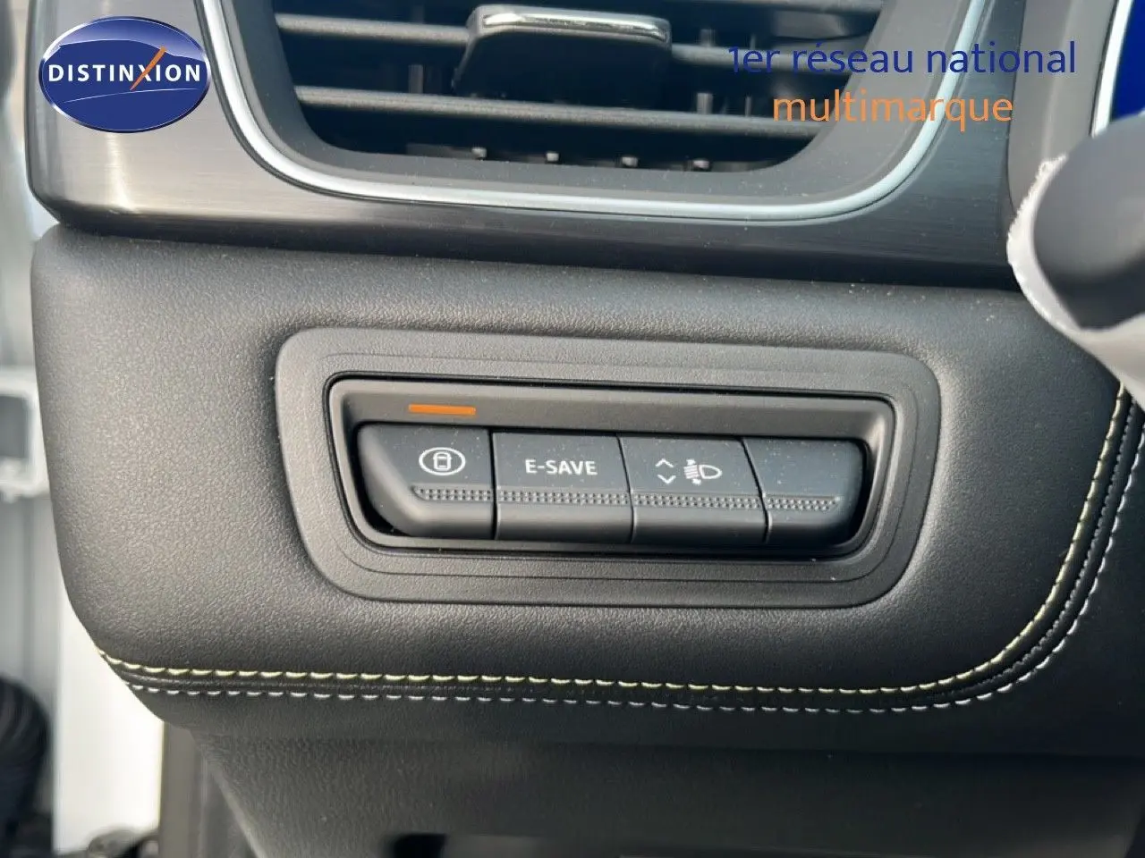 Gros plan sur les commandes de tableau de bord noir avec surpiqûres blanches dans la Renault Symbioz blanche nacrée.