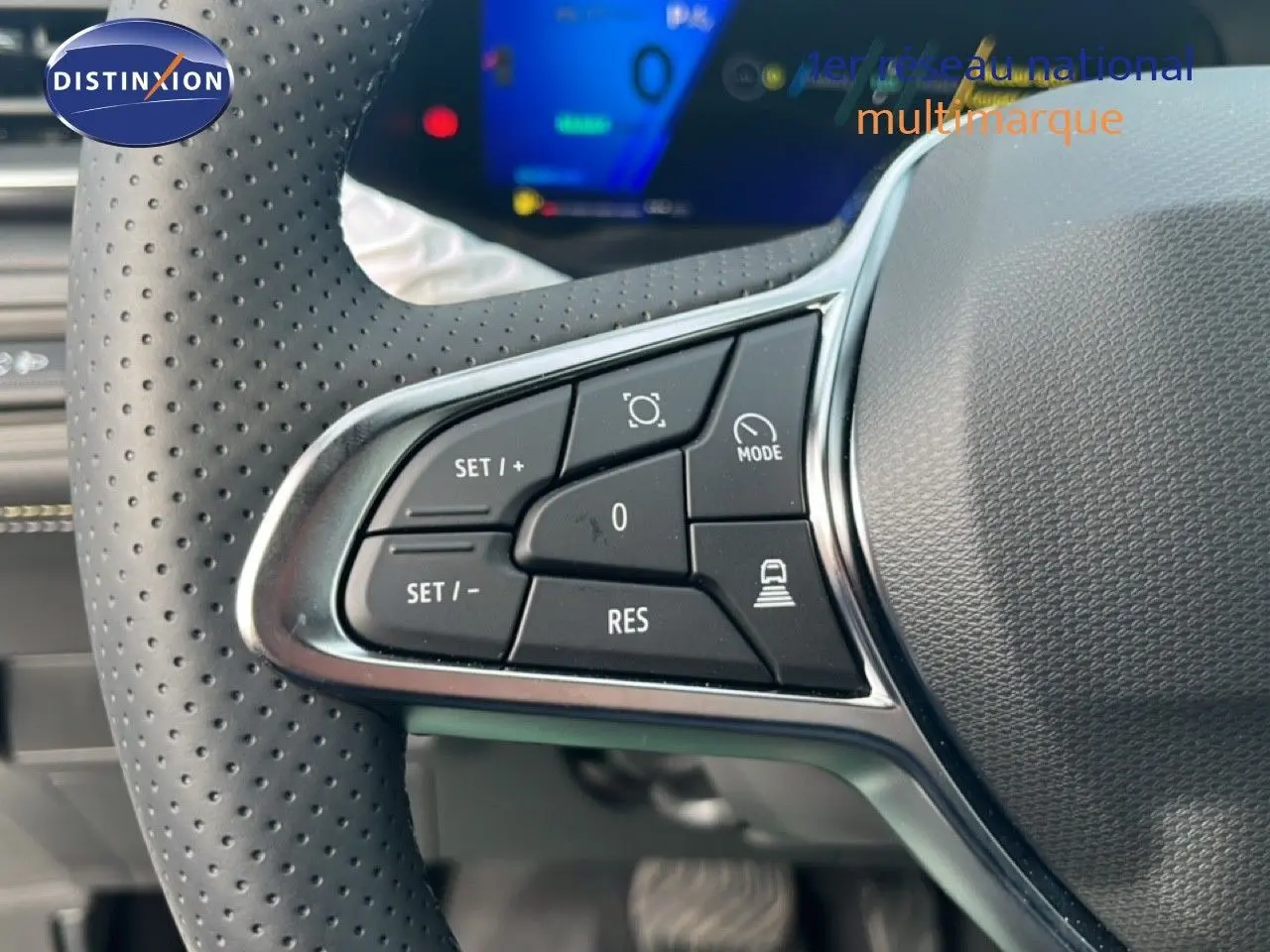 Gros plan sur les commandes de régulateur de vitesse au volant perforé d’une Renault Symbioz blanc nacré, intérieur moderne.