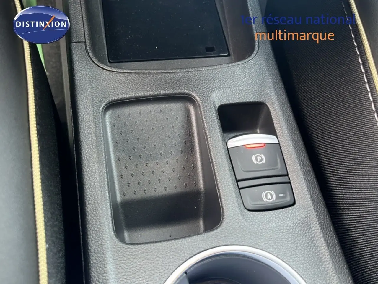 Gros plan sur la console centrale noire avec commandes de frein à main électrique et rangement du Renault Symbioz blanc nacré.