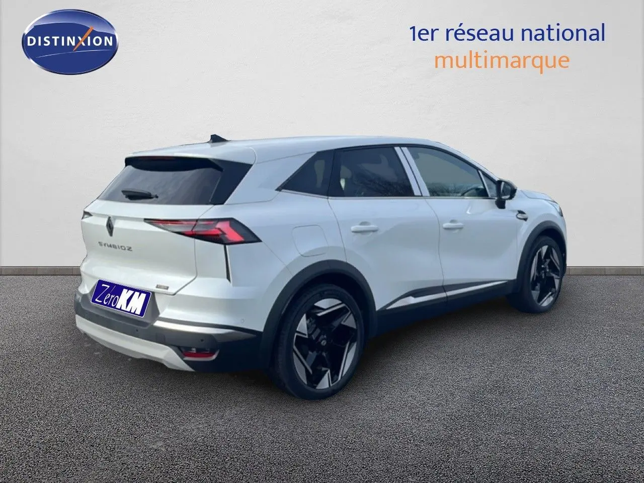 Renault Symbioz blanc nacré métal vu de trois quarts arrière droit, avec jantes noires distinctives et vitres teintées.