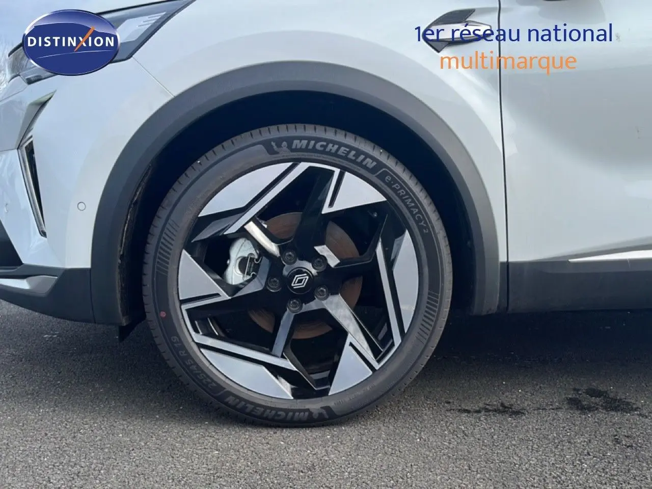 Gros plan sur la roue avant gauche du Renault Symbioz blanc nacré, mettant en valeur la jante noire et argentée au design moderne.