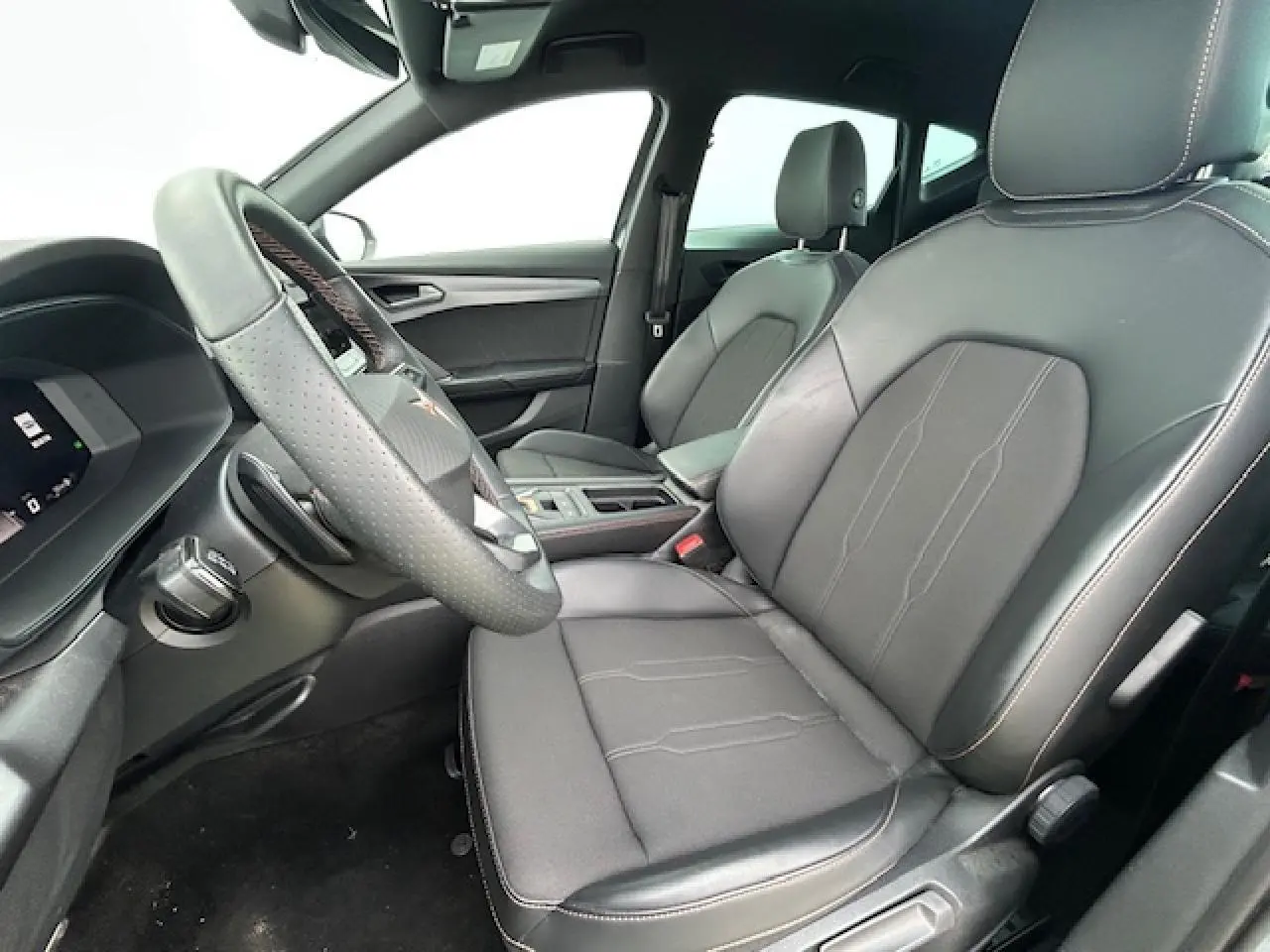 Vue intérieure côté conducteur du CUPRA Formentor 2025, sièges cuir noir avec surpiqûres contrastées et volant perforé.