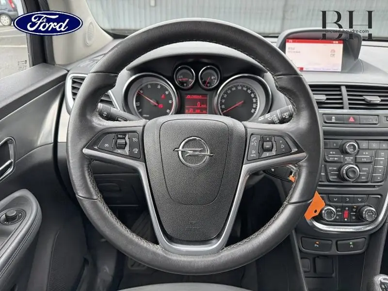 Vue intérieure centrée sur le volant cuir noir de l'Opel Mokka 2016 avec tableau de bord et écran multifonction.