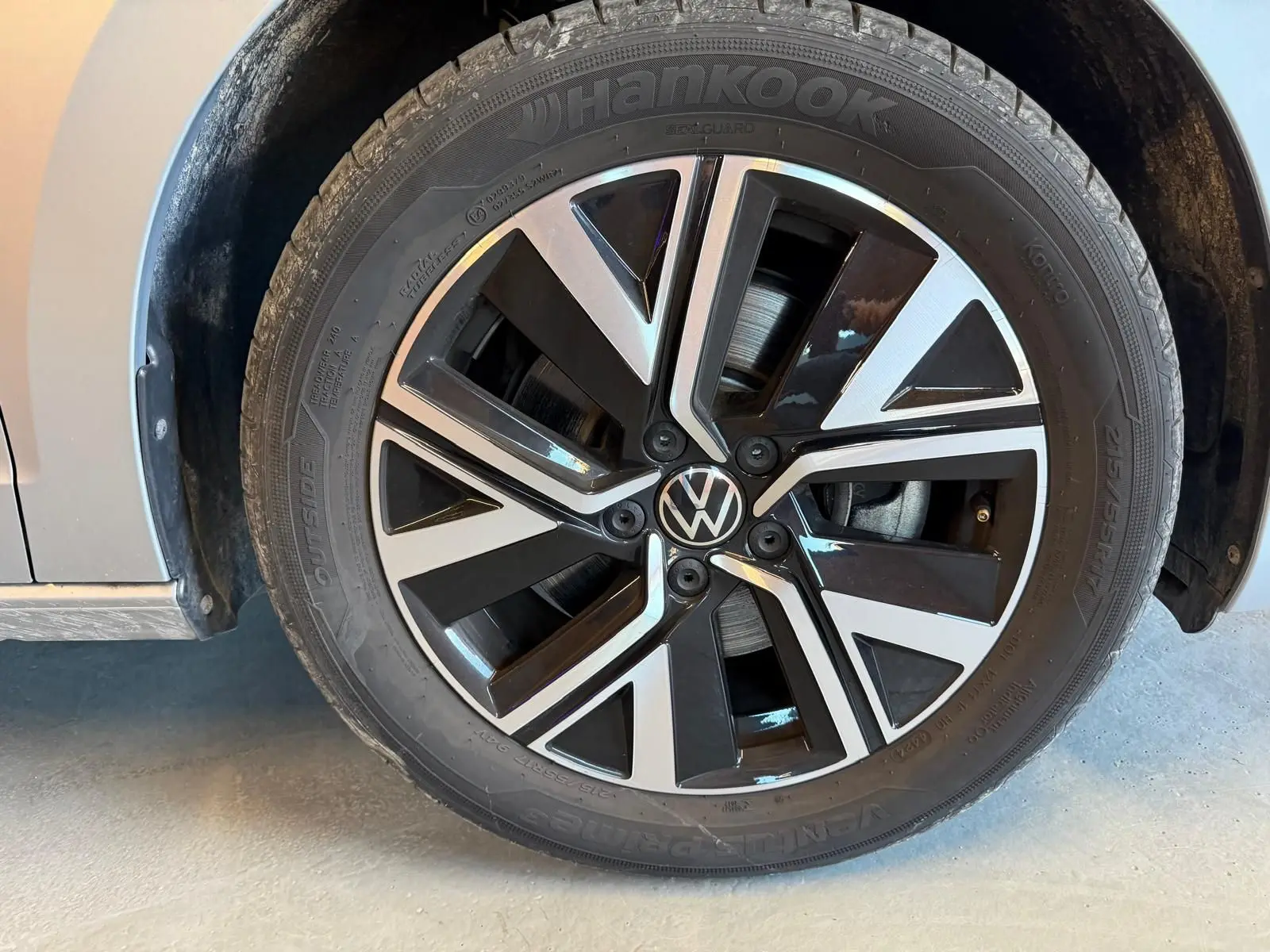 Gros plan sur la jante alliage noire et argentée du côté gauche d’un Volkswagen Touran gris 2025.