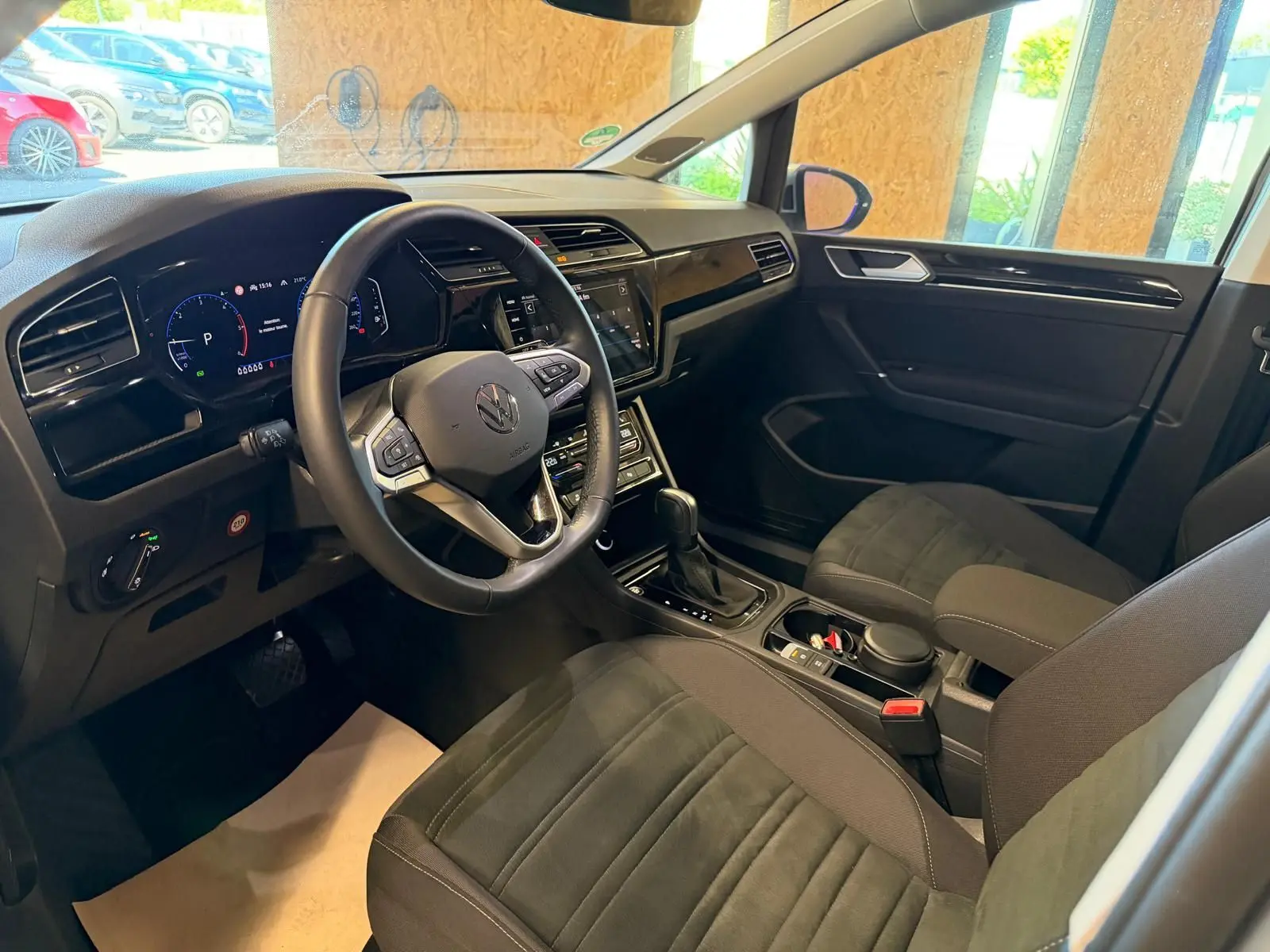 Vue intérieure côté conducteur du Volkswagen Touran 2025, volant cuir multifonctions et tableau de bord digital.