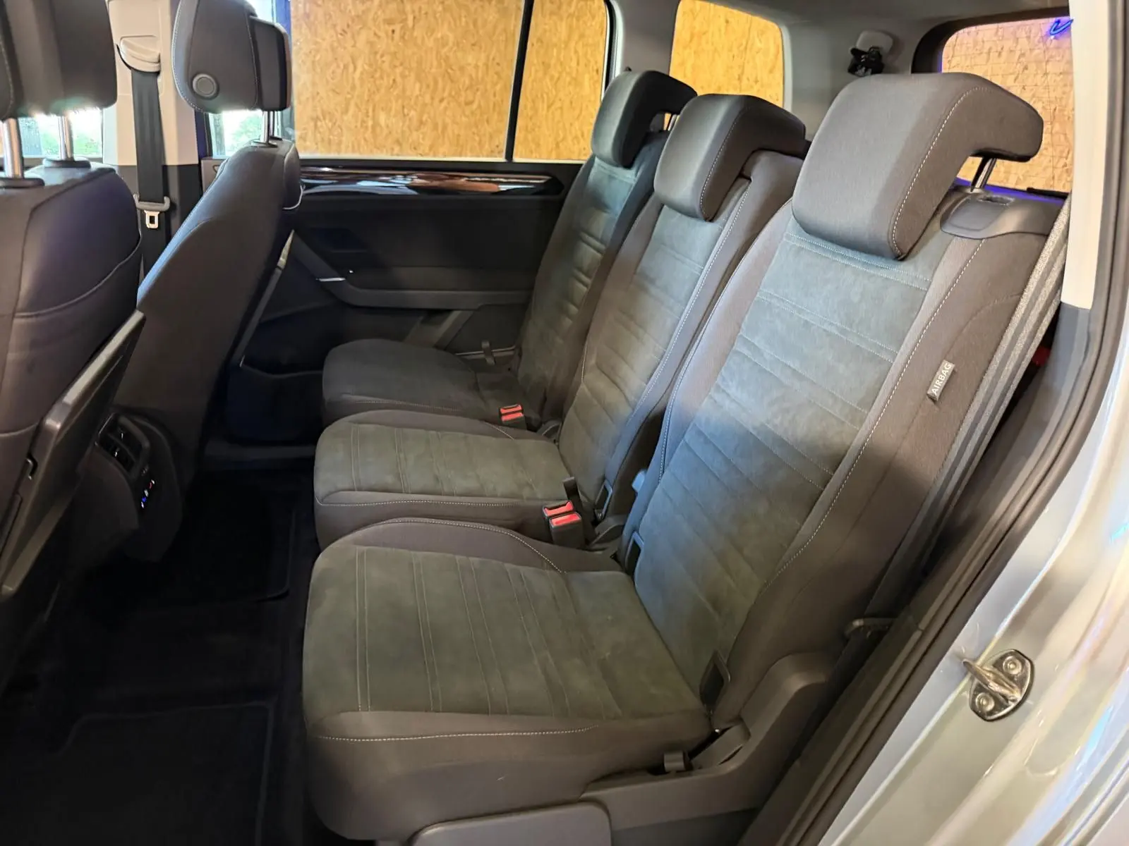 Vue latérale des sièges individuels arrière gris foncé du Volkswagen Touran 2025, avec habillage tissu et ceintures visibles.