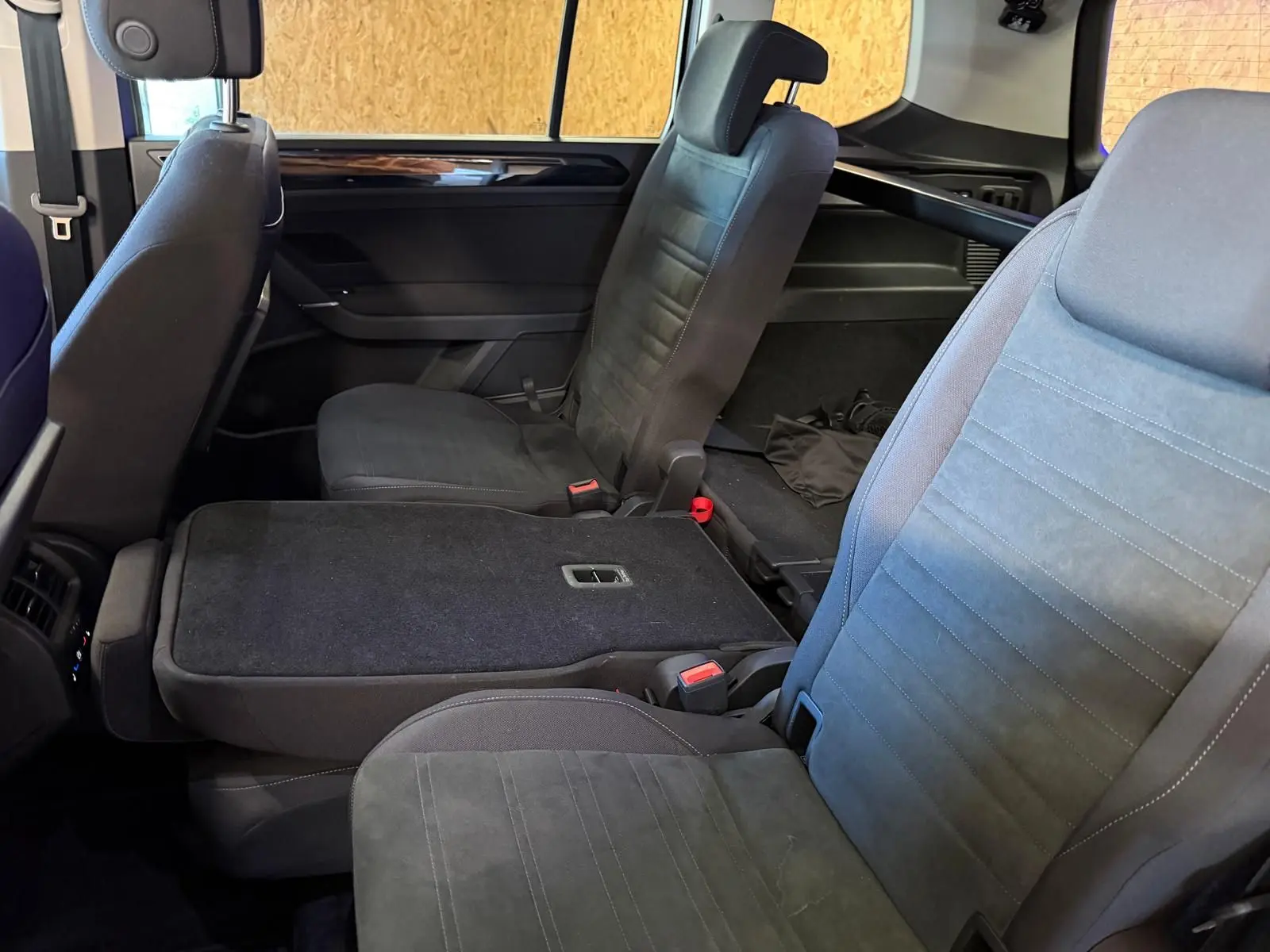 Vue intérieure côté droit sur les sièges noirs de la 2ème rangée du Volkswagen Touran gris 2025, avec siège central rabattable.