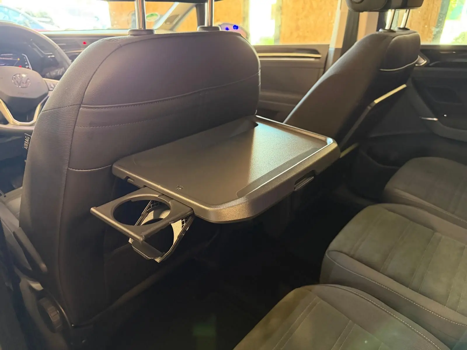 Vue intérieure du Volkswagen Touran 2.0 TDI gris, tablette pliable et porte-gobelet au dos du siège avant droit.