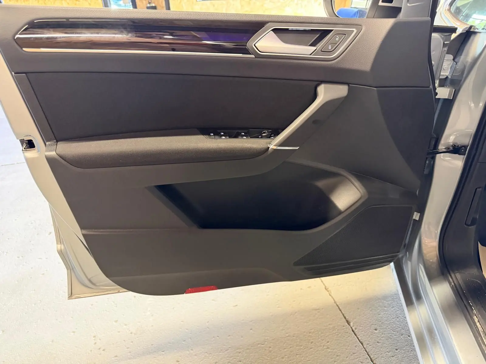 Vue intérieure de la porte avant gauche grise du Volkswagen Touran 2025 avec garniture noire et insert chromé.