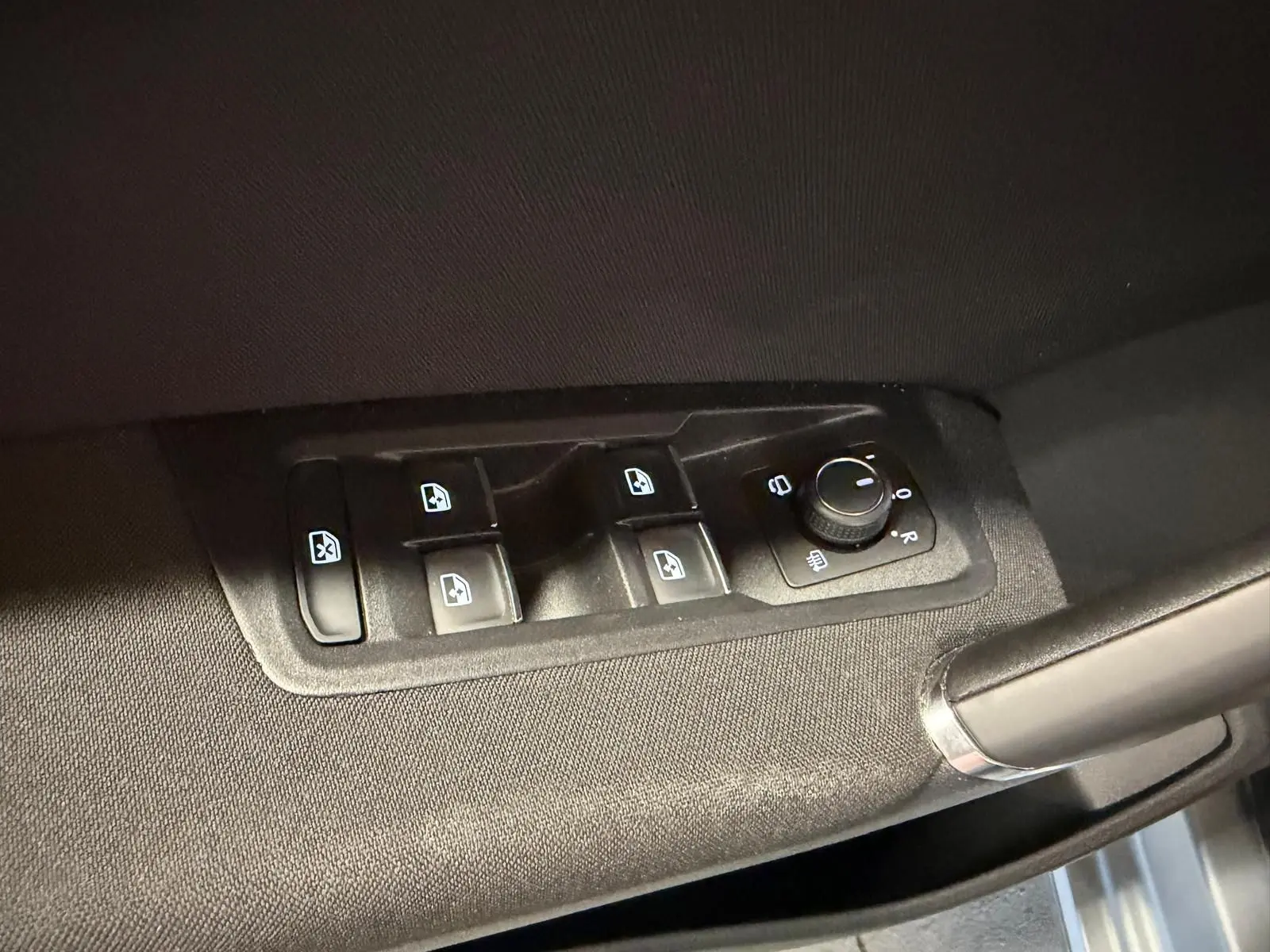Commande des vitres électriques et réglage des rétroviseurs sur la porte côté conducteur d’un Volkswagen Touran gris.