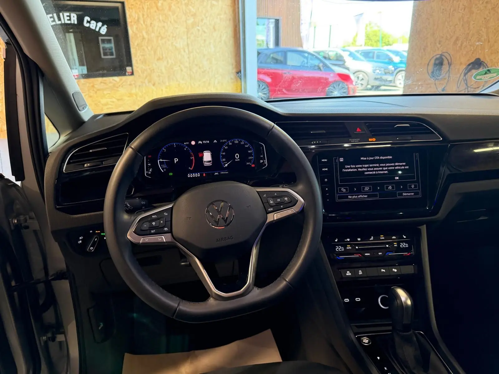 Vue intérieure centrée sur le volant cuir multifonctions et le tableau de bord numérique du Volkswagen Touran gris 2025.