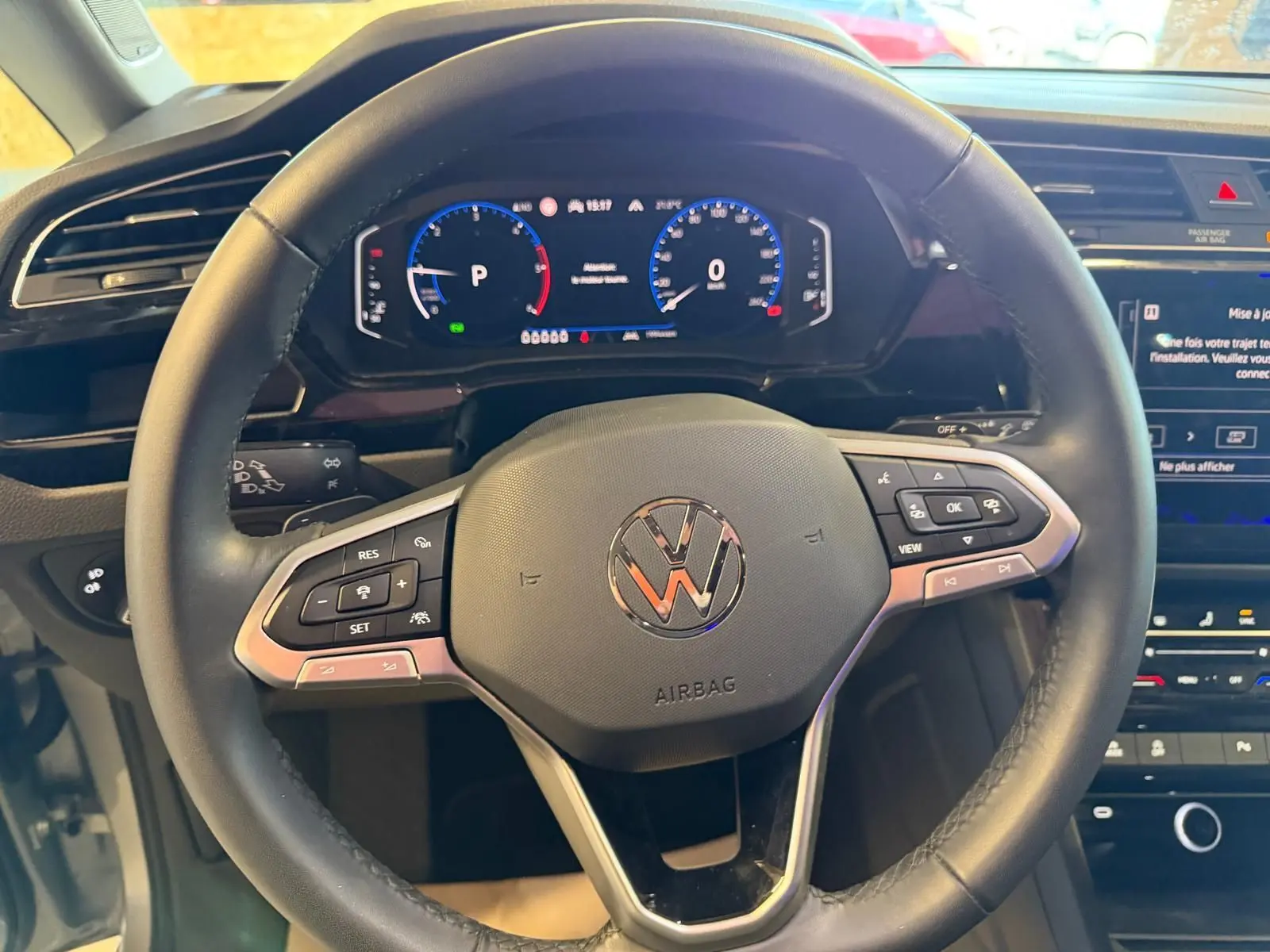 Vue rapprochée du volant cuir multifonctions noir du Volkswagen Touran 2025 avec tableau de bord digital et écran tactile.