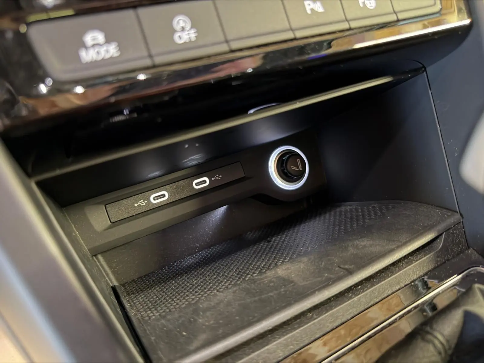Gros plan sur la console centrale noire du Volkswagen Touran 2025, montrant deux ports USB-C et une prise 12V éclairée.