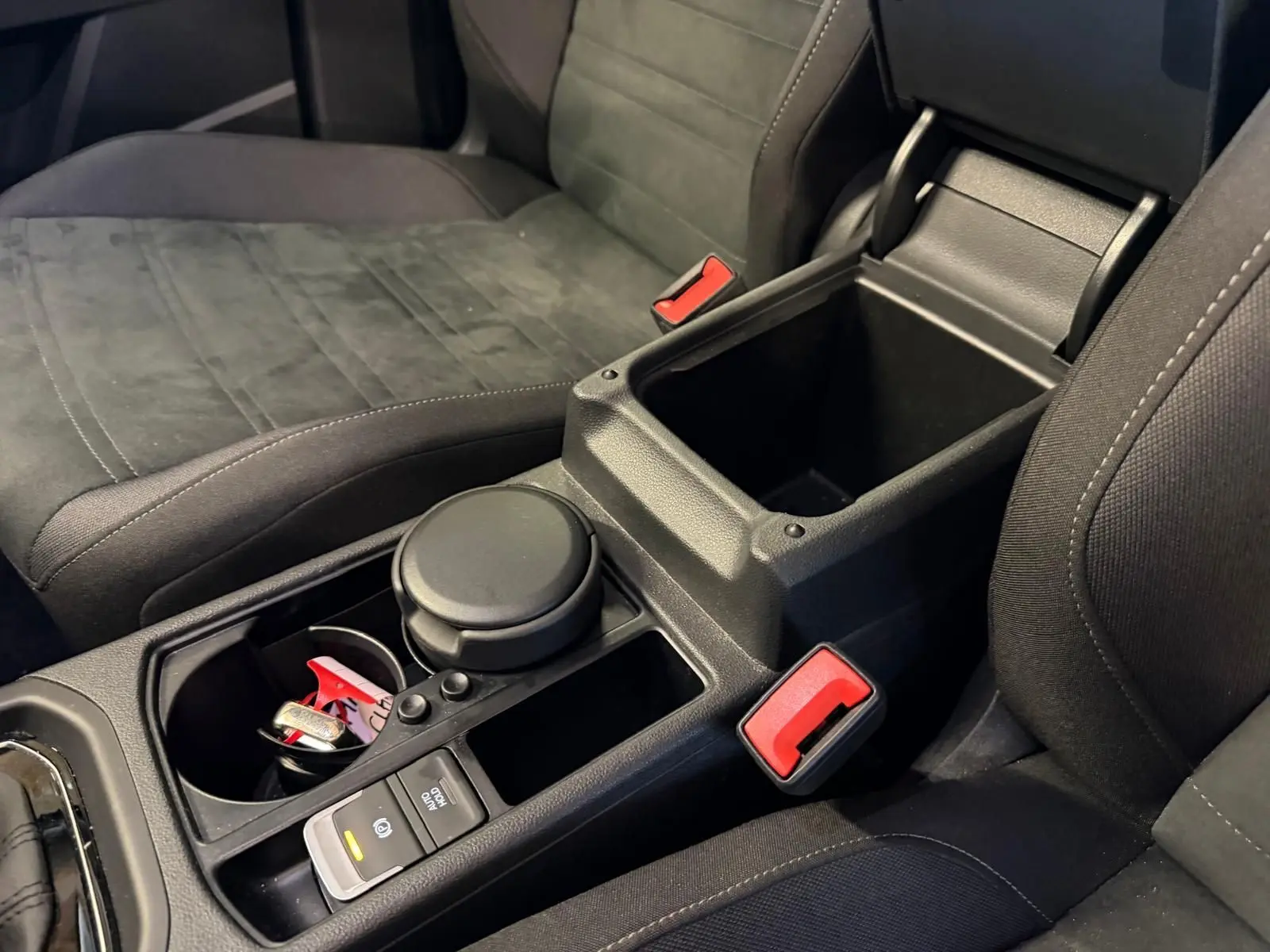 Vue rapprochée de la console centrale noire entre les sièges avant gris foncé du Volkswagen Touran 2025.