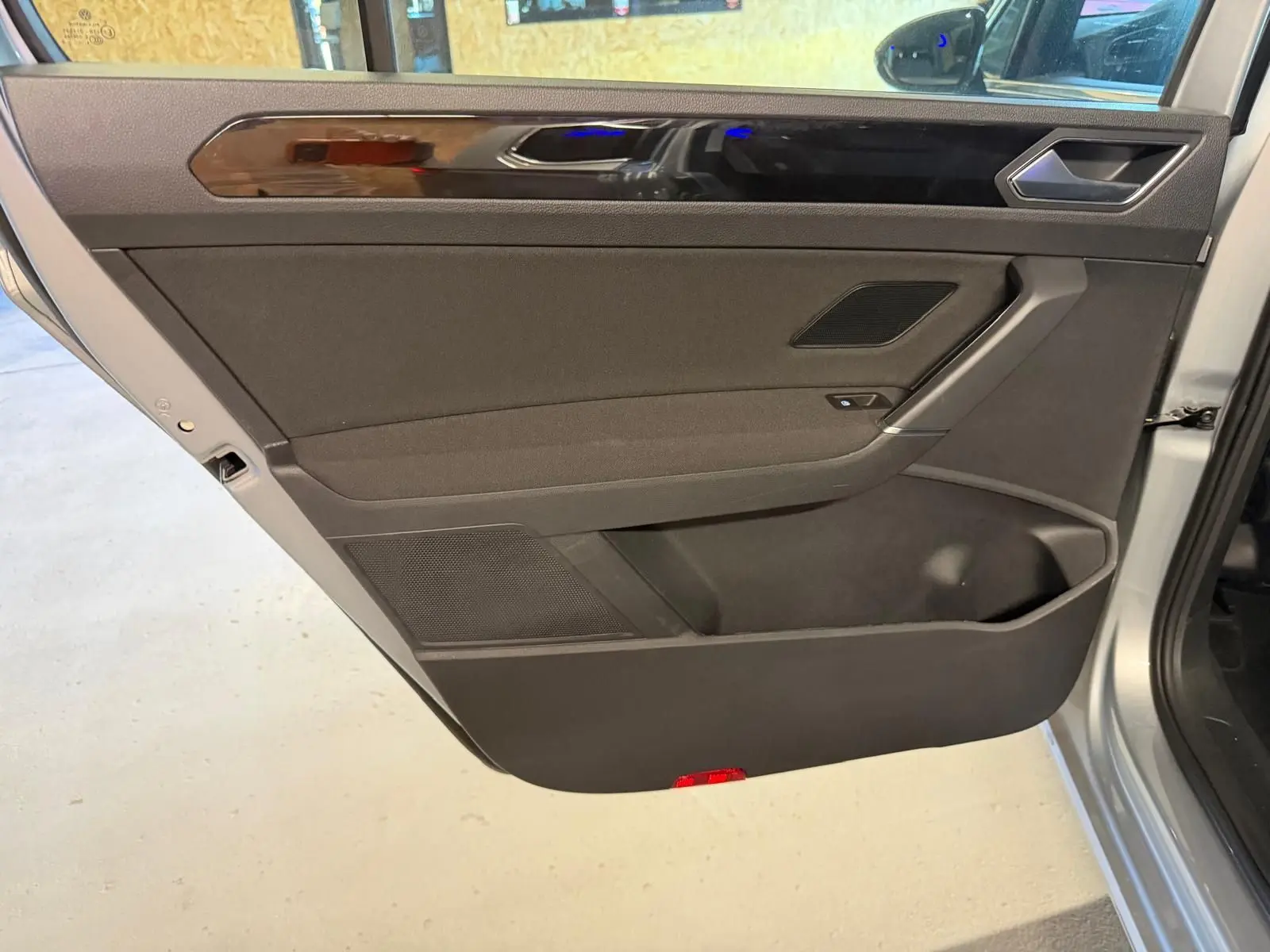 Vue intérieure de la porte arrière gauche gris clair du Volkswagen Touran 2025 avec garniture noire et insert brillant.