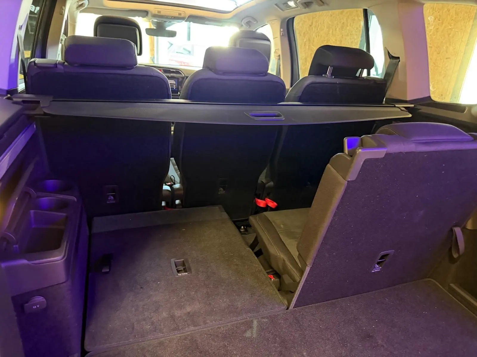 Vue arrière intérieure du Volkswagen Touran gris 2025, montrant les sièges rabattables et la tablette de coffre.