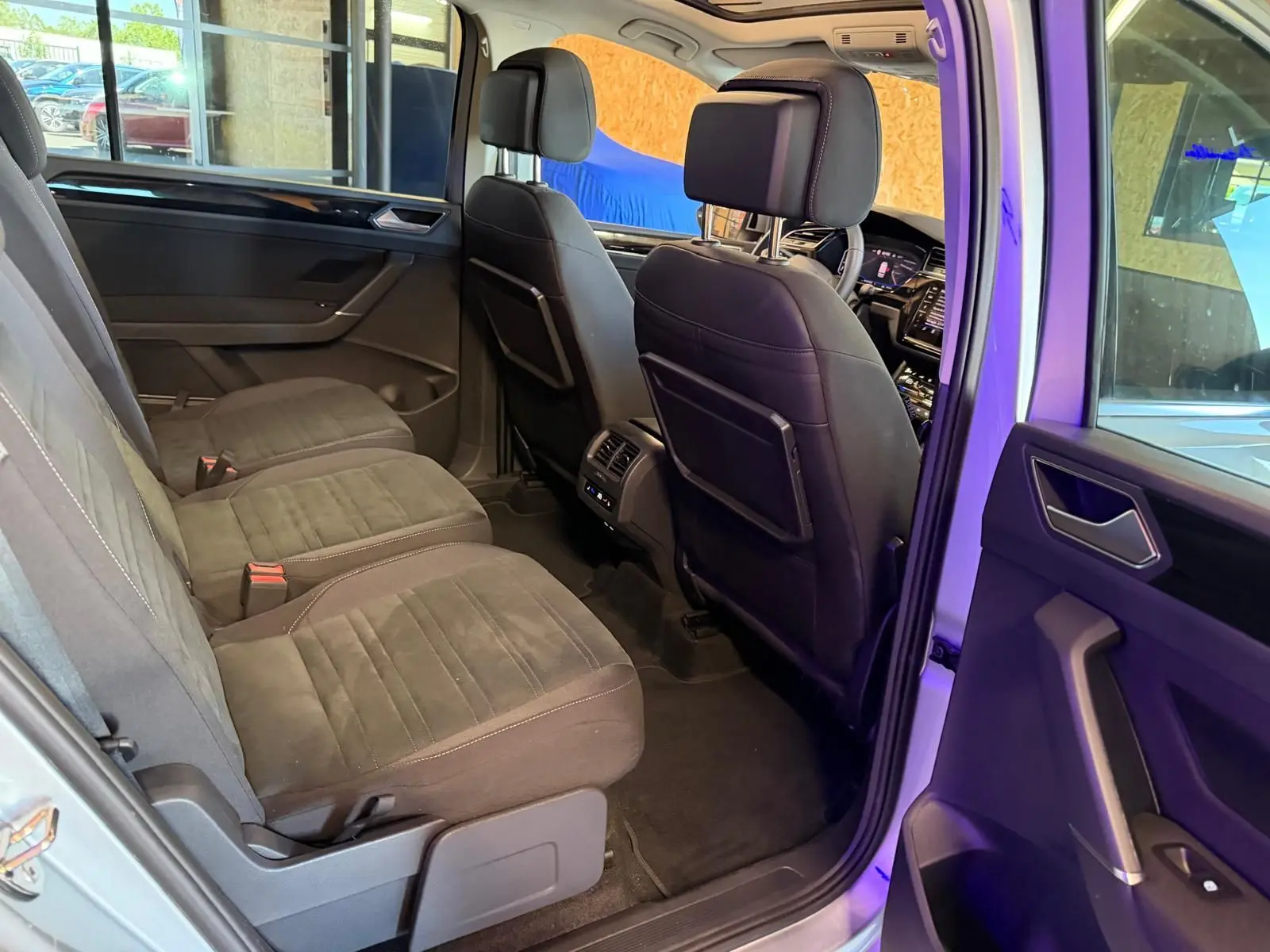 Vue intérieure côté gauche de la 2ème rangée du Volkswagen Touran gris 2025, sièges individuels et rangements visibles.