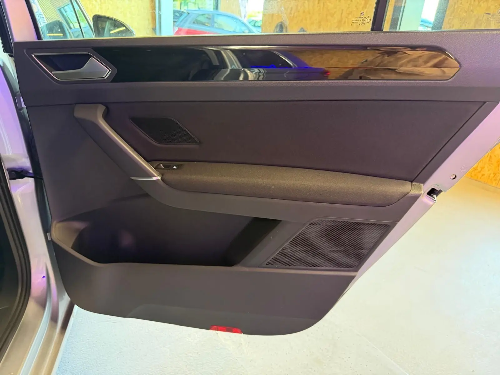 Vue intérieure côté gauche de la porte avant grise du Volkswagen Touran 2025 avec insert décoratif noir brillant.