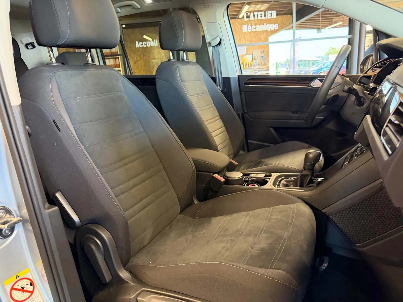 Vue intérieure côté conducteur du Volkswagen Touran gris 2025, mettant en valeur les sièges avant en tissu et alcantara.
