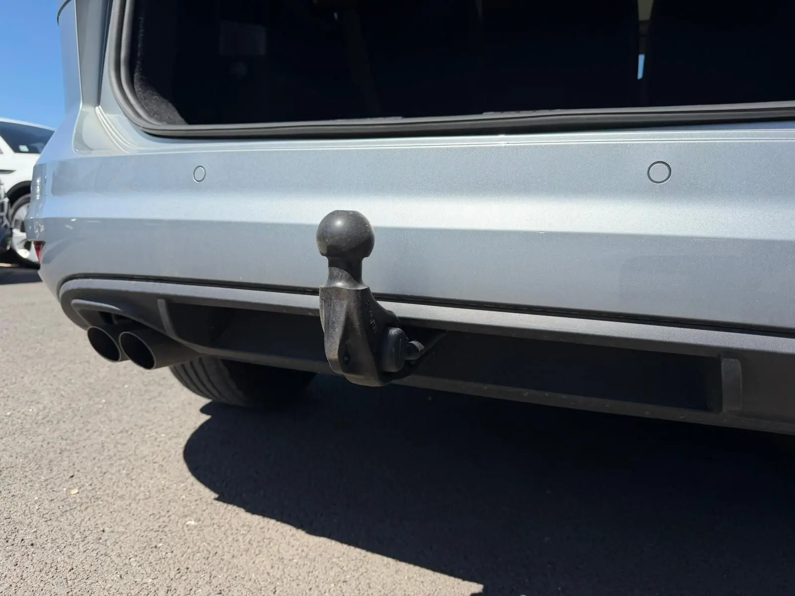 Gros plan sur l'attelage arrière noir du Volkswagen Touran gris 3/4 arrière avec double sortie d'échappement visible.