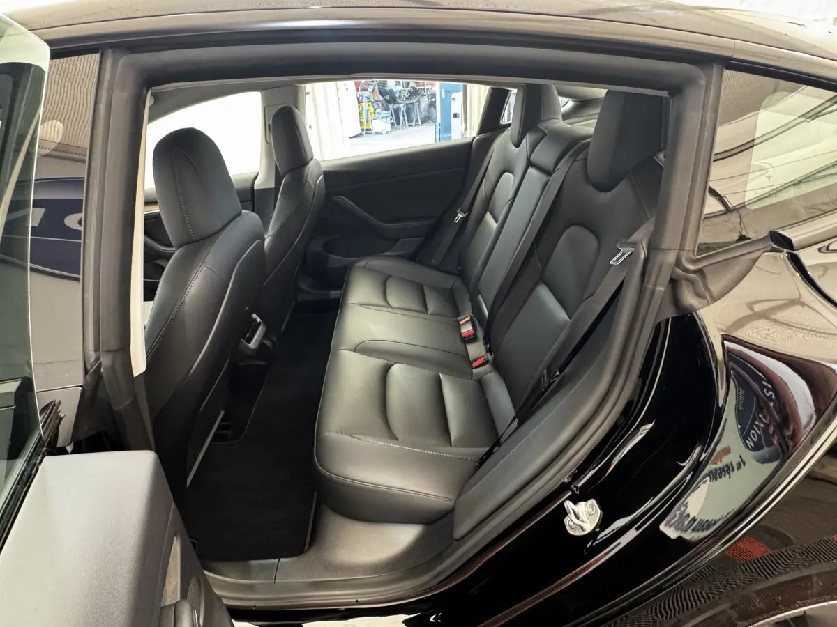 Vue intérieure côté droit montrant la banquette arrière en cuir noir d'une Tesla Model 3 Grande Autonomie 2023.