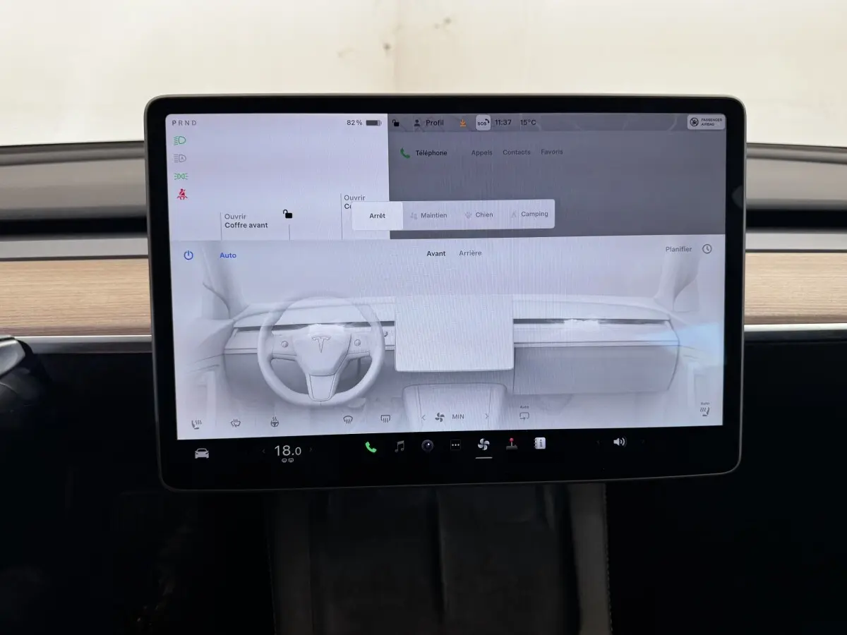 Écran tactile central allumé dans l’habitacle d’une Tesla Model 3 noire, vue frontale rapprochée.