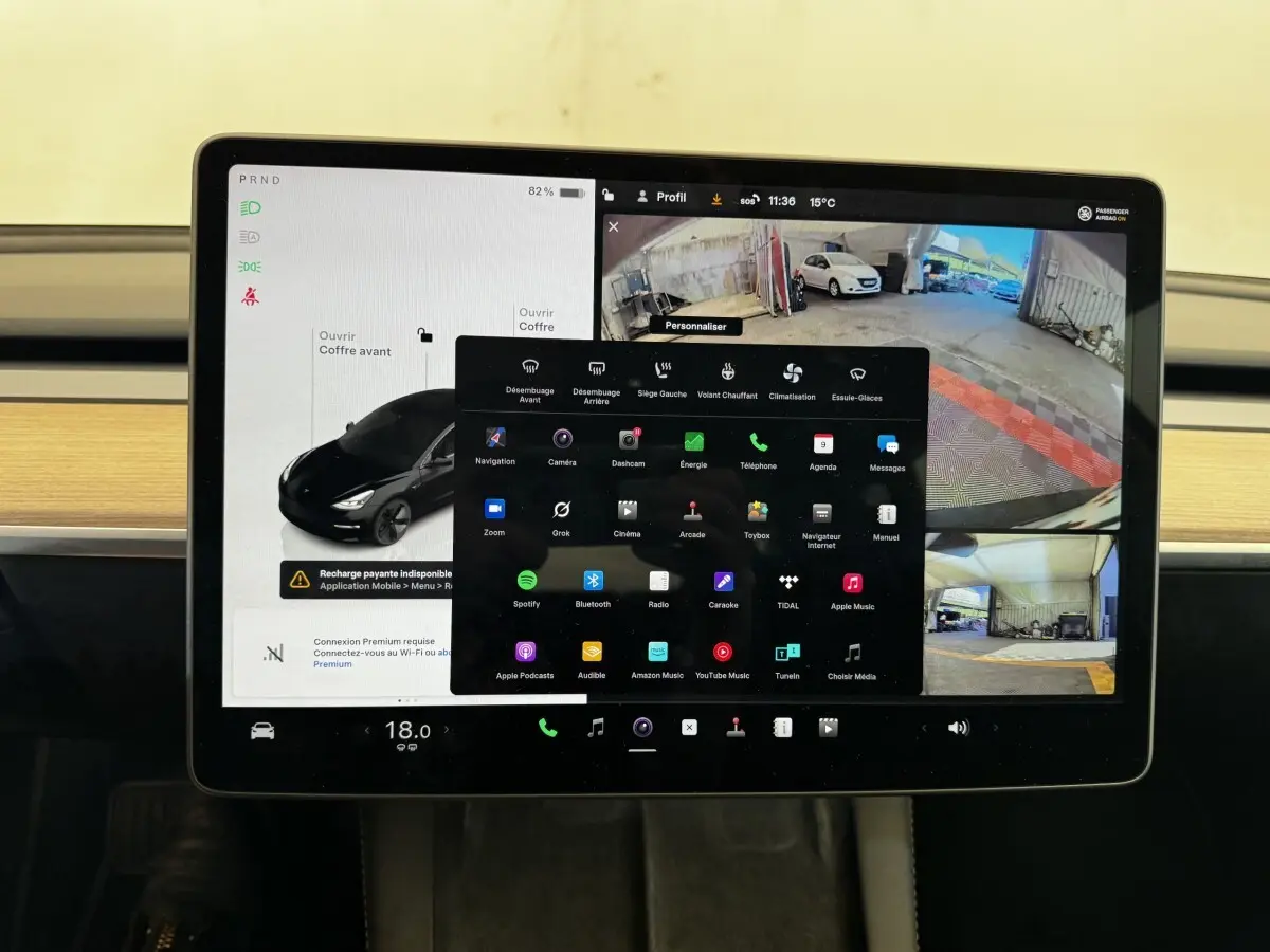 Écran tactile central de la Tesla Model 3 noir 2023 affichant la caméra de recul et le menu multimédia.