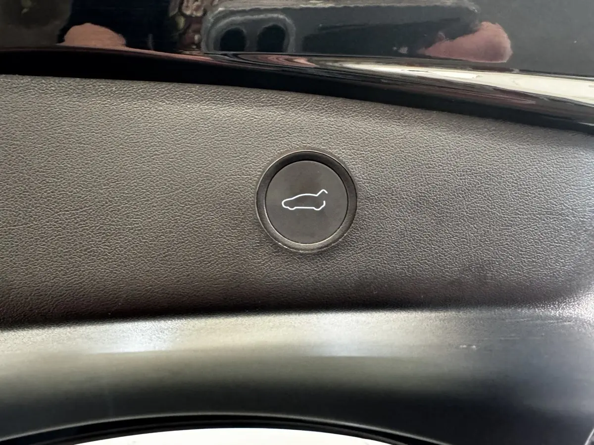 Bouton d'ouverture électrique du coffre sur panneau intérieur noir d'une Tesla Model 3 Grande Autonomie 2023.