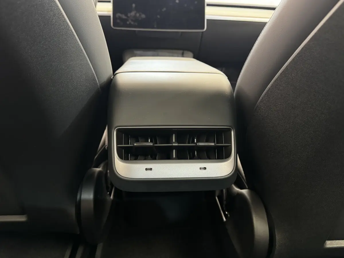 Gros plan sur la console centrale arrière noire de la Tesla Model 3 2023 avec bouches d’aération et ports USB-C.