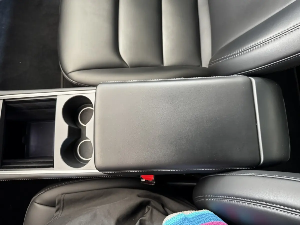 Vue plongeante sur l'accoudoir central noir et les sièges en cuir noir de la Tesla Model 3 Grande Autonomie 2023.