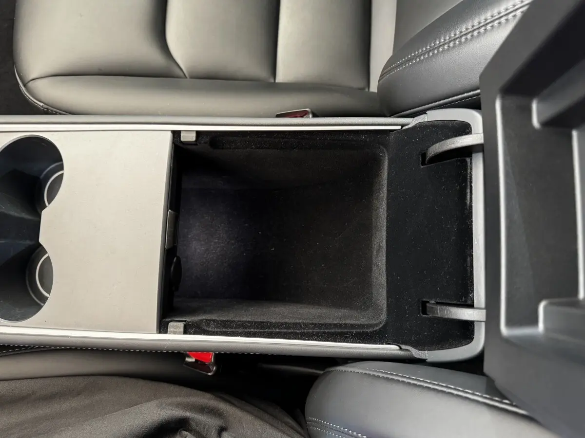 Vue plongeante sur la console centrale noire ouverte de la Tesla Model 3 Grande Autonomie 2023.