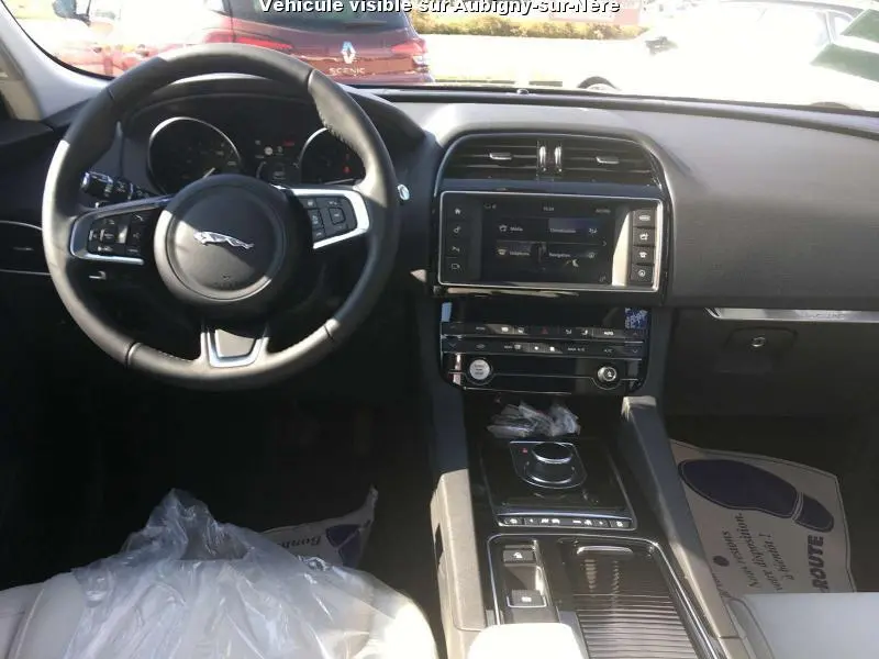 Vue intérieure avant de la Jaguar F-PACE noire, montrant le volant multifonctions, l’écran tactile central et la console moderne.