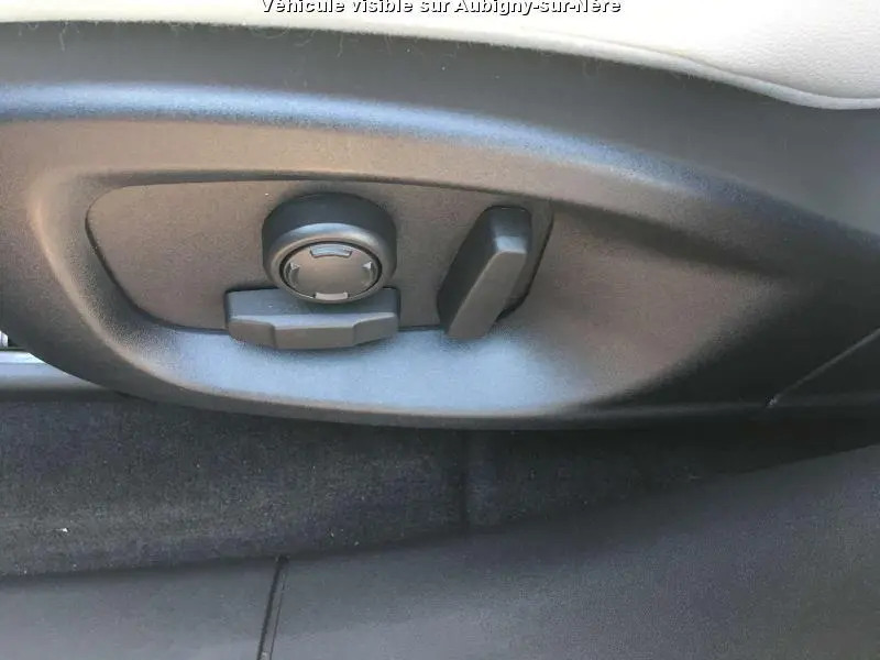 Gros plan sur les commandes électriques de réglage du siège avant d'une Jaguar F-PACE noire, intérieur sombre.