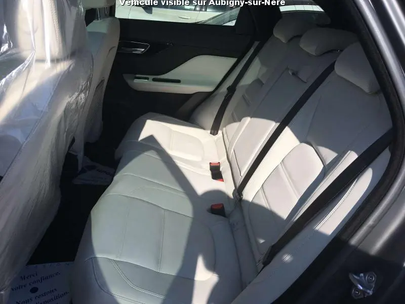 Vue intérieure côté droit des sièges arrière en cuir clair du Jaguar F-PACE 2.0 D noir, avec ceinture de sécurité visible.