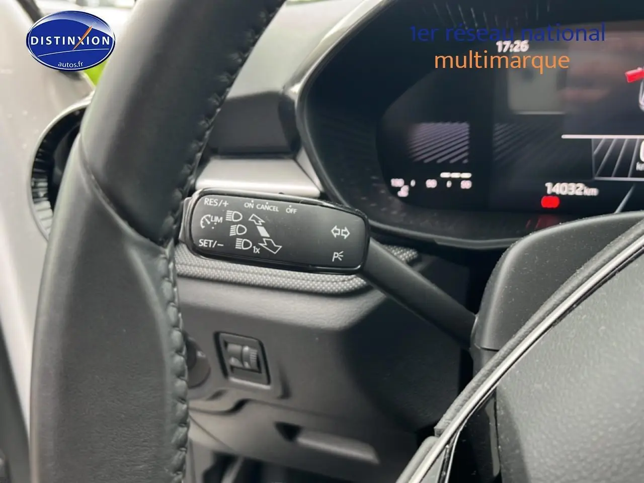 Gros plan sur la commande multifonction noire à gauche du volant cuir d'une Skoda Fabia blanche, tableau de bord numérique visible.