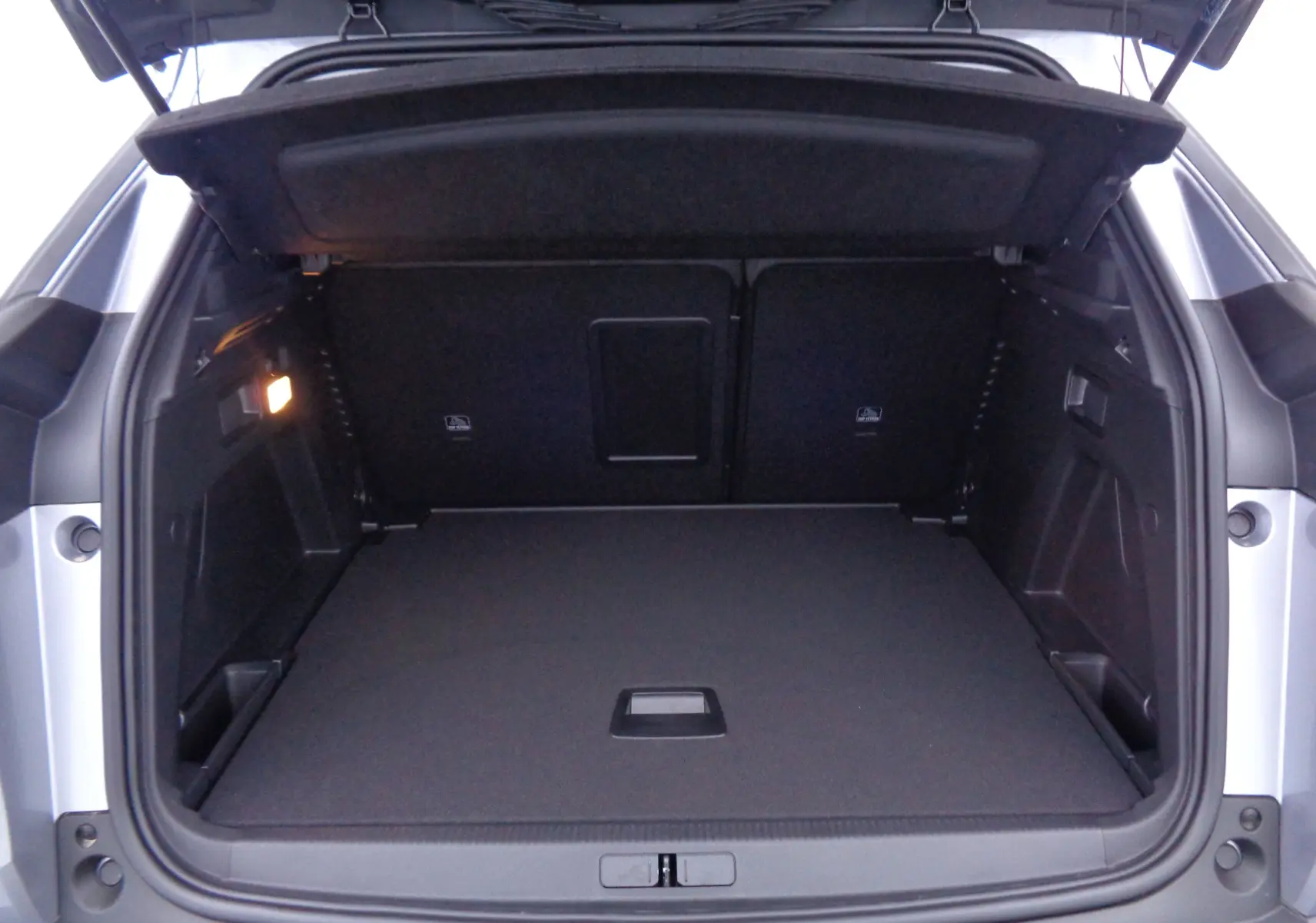 Coffre ouvert vu de l'arrière d'un Peugeot 3008 gris Artense Metal, montrant un espace de chargement propre et spacieux.