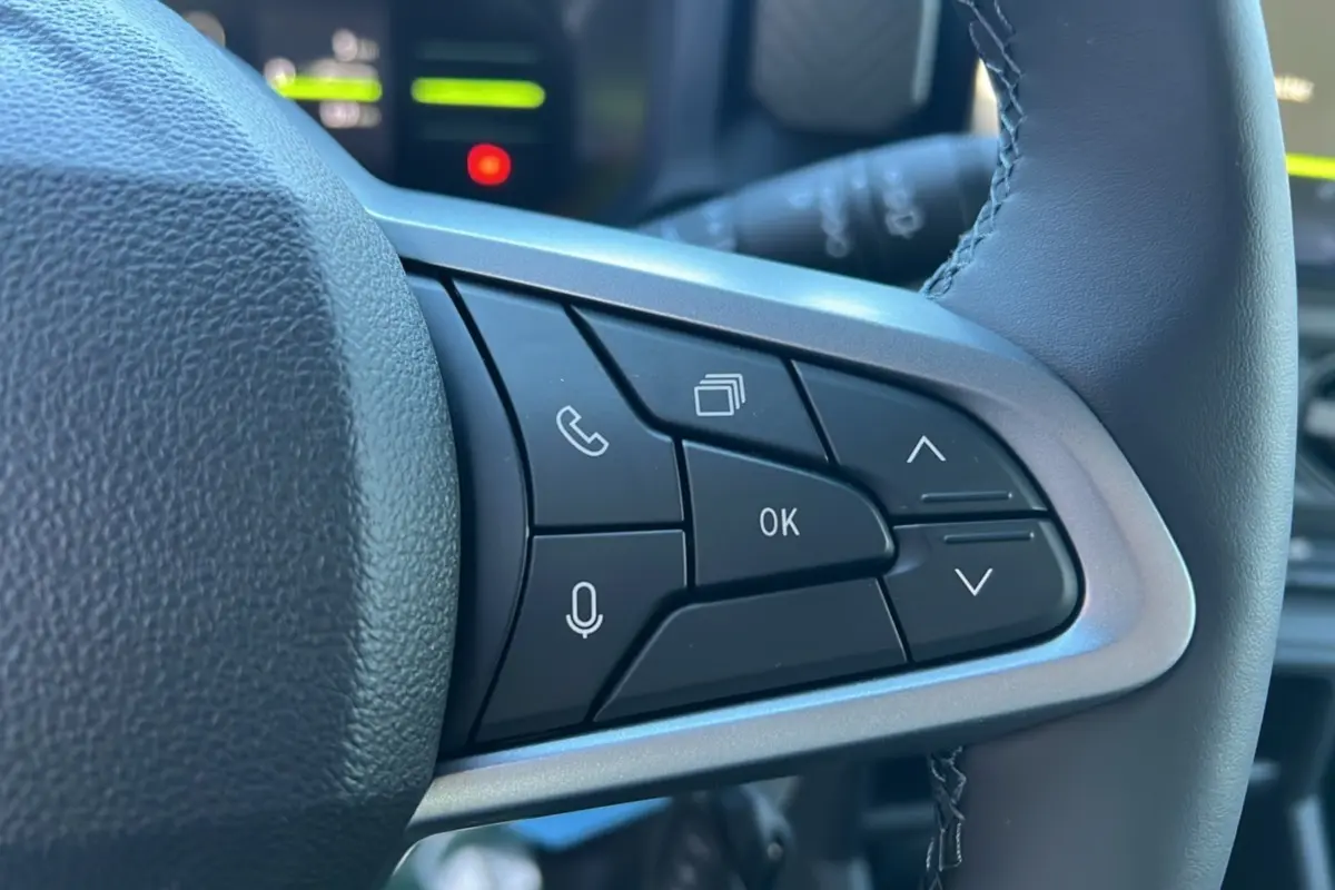 Gros plan sur les commandes au volant du Dacia Duster 2025, version Mild Hybrid 130 4x4 Expression, cuir noir et boutons multifonctions.