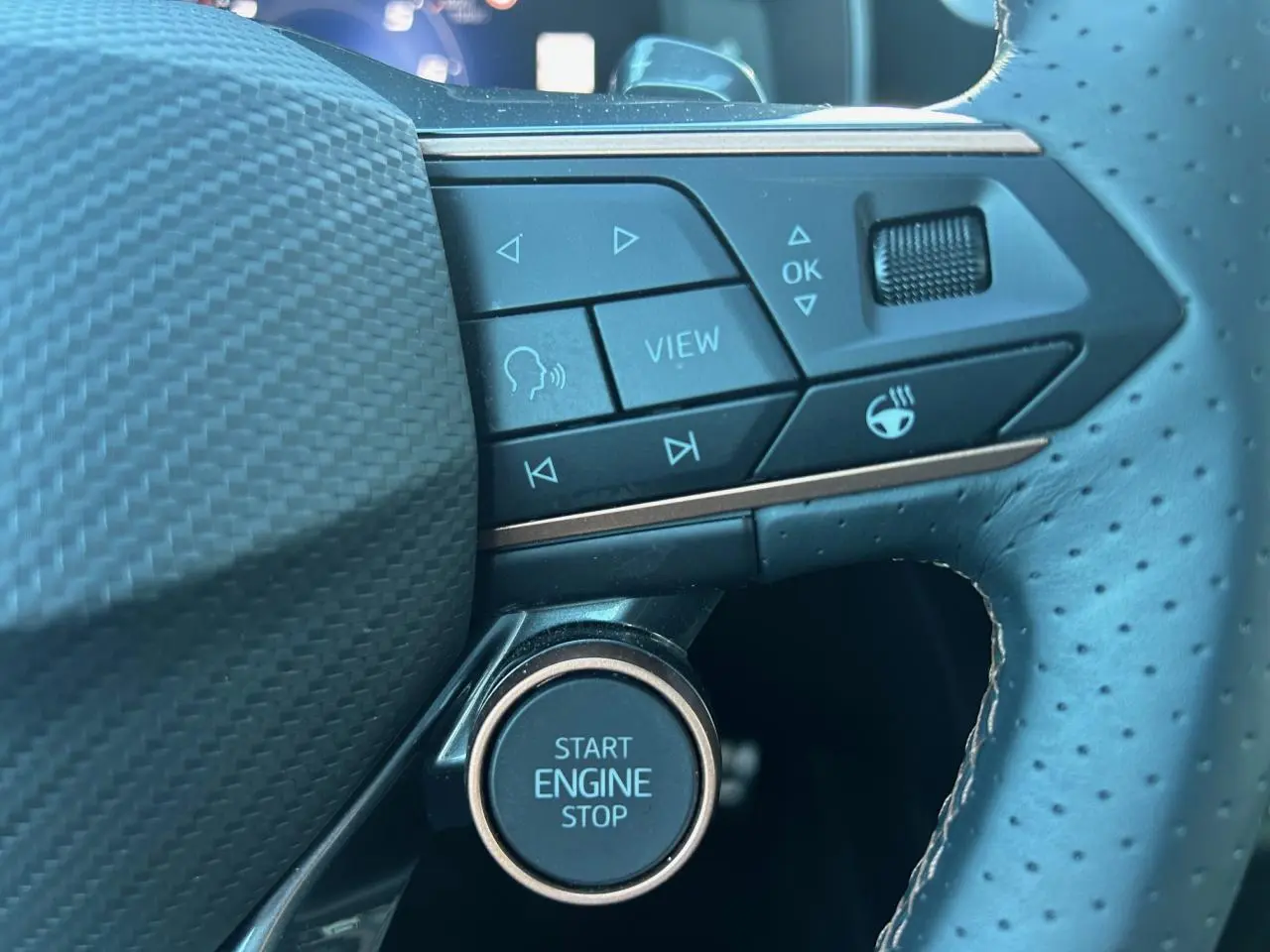 Gros plan sur les commandes et le bouton start/stop du volant perforé en cuir noir du CUPRA Formentor blanc neige.