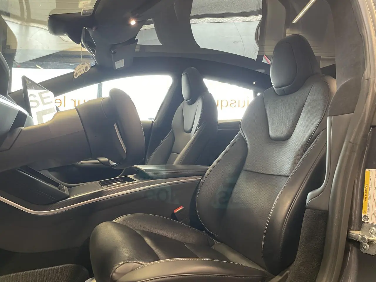 Vue intérieure côté droit du Tesla Model S Plaid 2023, sièges en cuir noir avec finitions en fibre de carbone.